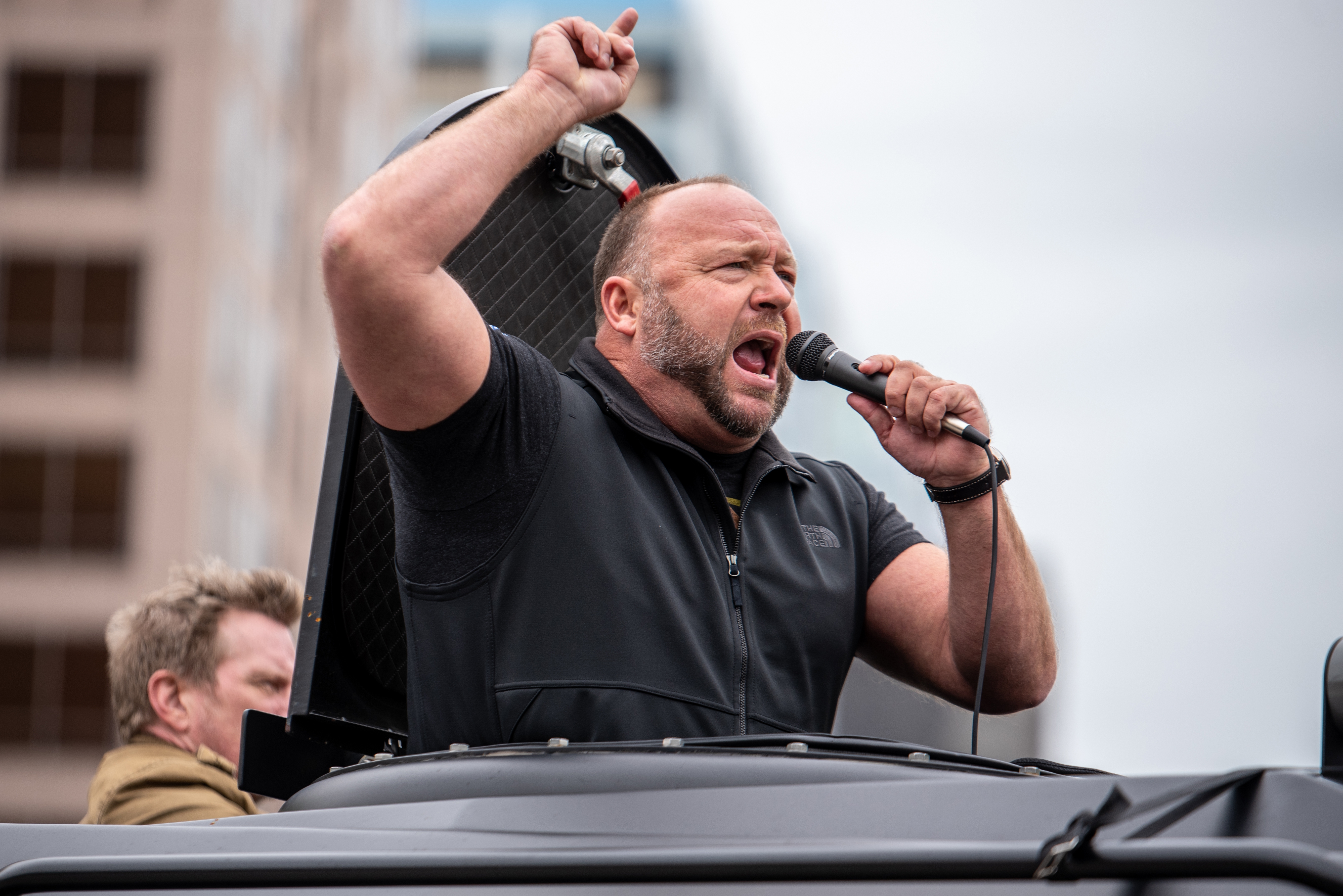 Person speaking passionately into a microphone atop a conveyance  during a nationalist   event