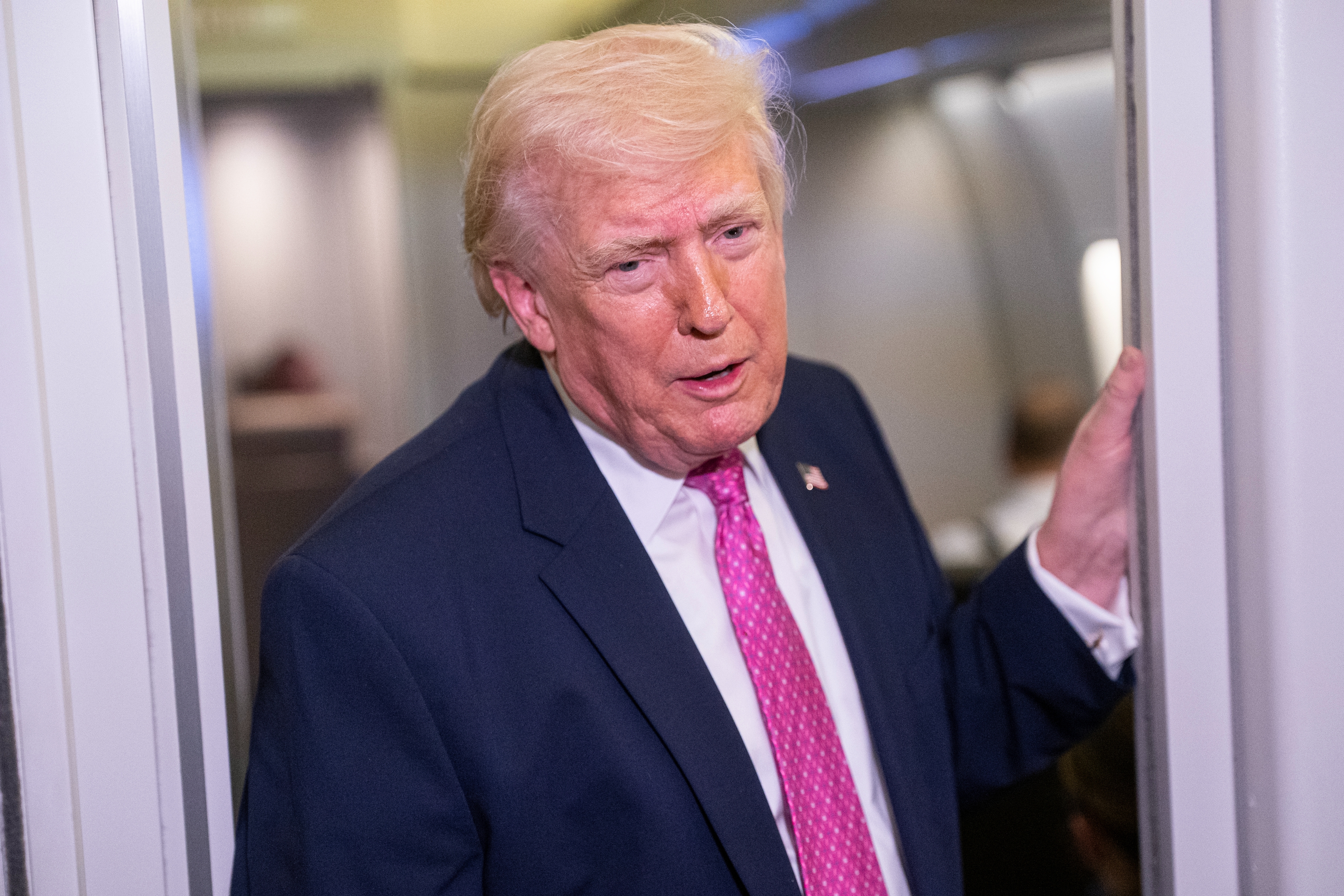 A antheral   successful  a suit   and pinkish  necktie  stands successful  an airplane doorway, speaking oregon  astir  to prosecute  successful  conversation