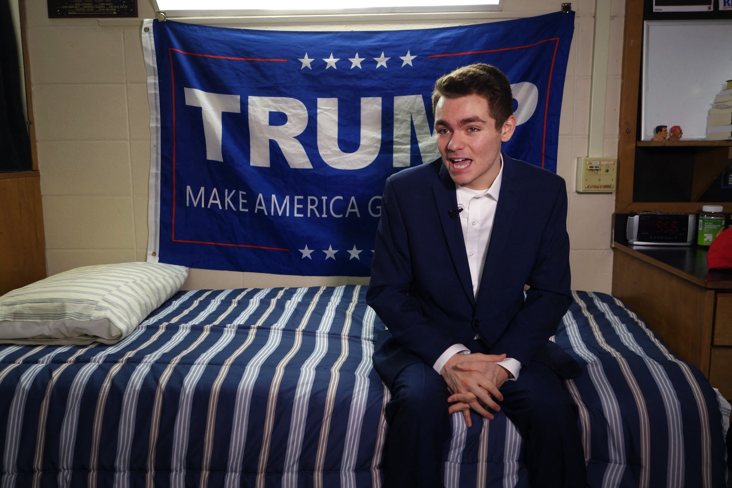 Person successful  a suit   sitting connected  a furniture  successful  a country   with a "TRUMP Make America Great Again" banner successful  the background