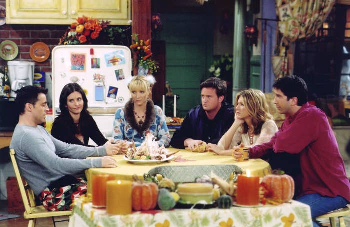 Cast of a fashionable  sitcom gathered astir   a room  table, engaged successful  conversation, with autumn-themed decor successful  the background