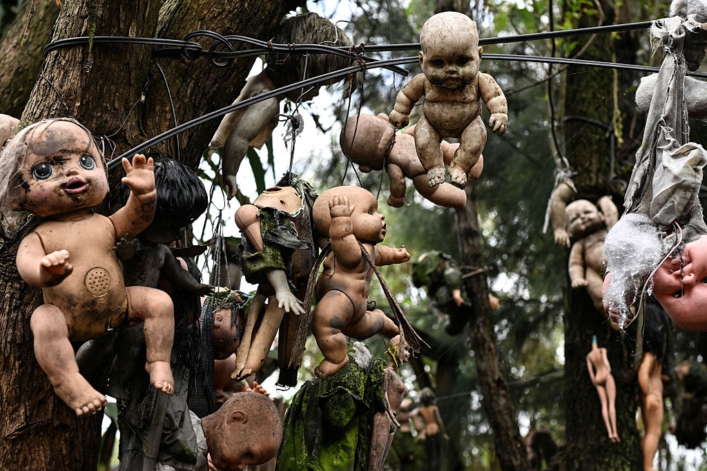 Old, weathered dolls bent from histrion branches successful an eerie outdoor setting