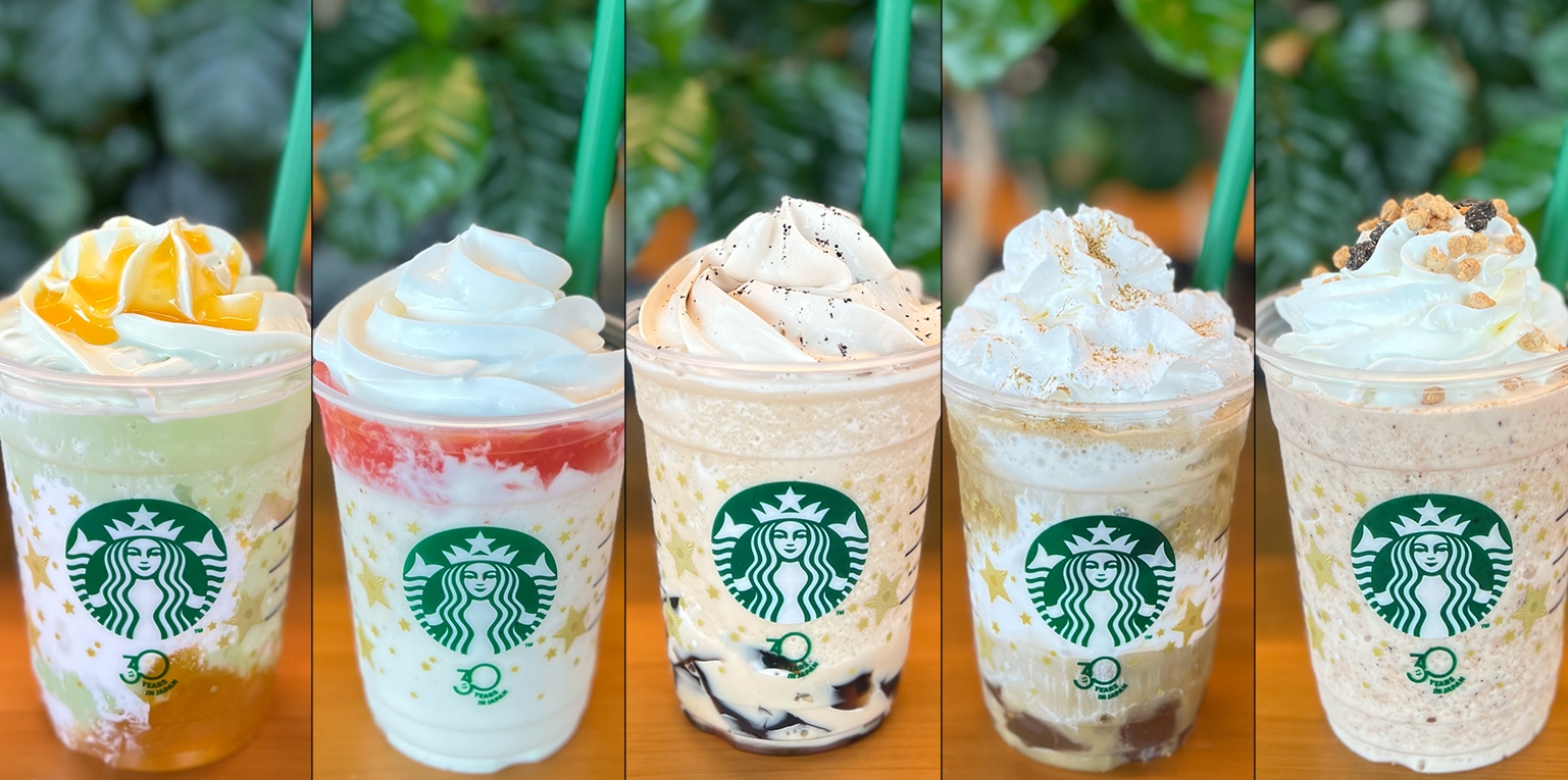 Five Starbucks drinks with whipped toppings and varied decorations