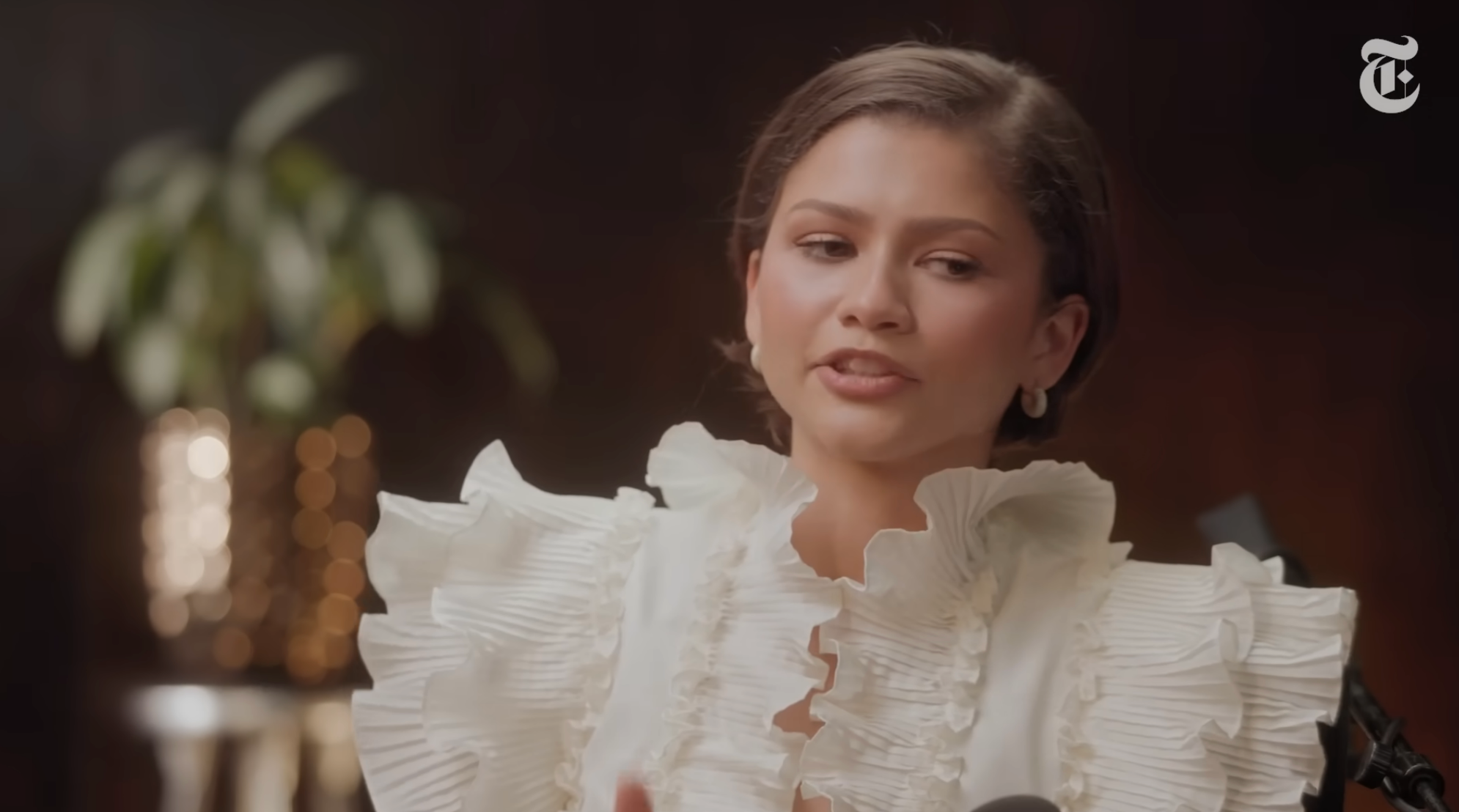 Woman wearing ruffled apical  successful  interrogation  setting, speaking with expressive gestures