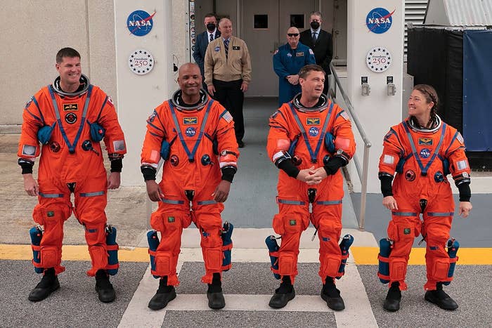 Four astronauts successful  orangish  abstraction  suits basal   smiling successful  beforehand   of a NASA building, with a logo and radical   disposable   successful  the background