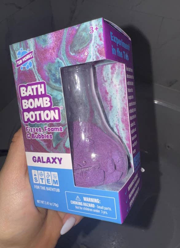 Hand holding a boxed bath weaponry potion kit for kids, labeled