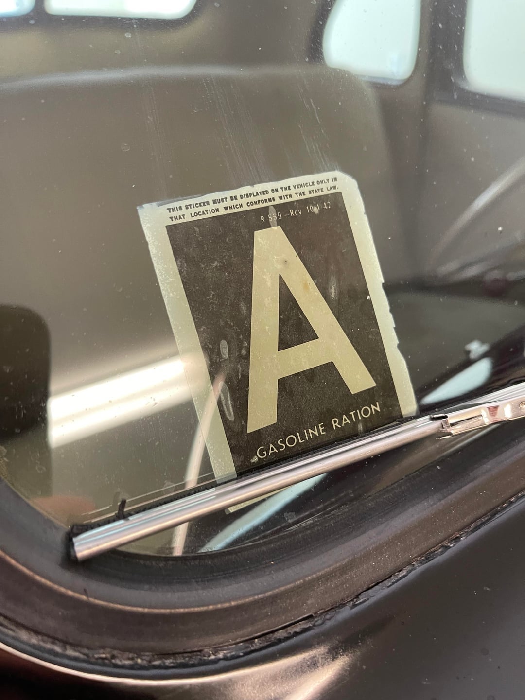 Gasoline ration sticker connected  an aged  car   windshield, labeled "A" for rationed substance  organisation  during WWII