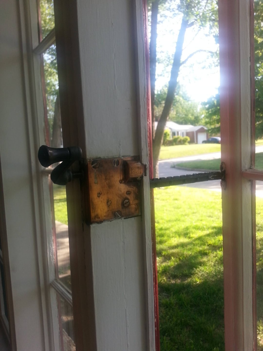 Close-up of a vintage doorway  latch connected  a solid  doorway  with a presumption    of a sunny suburban thoroughfare  outside