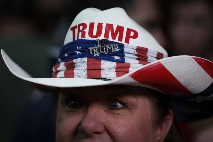 Person wearing a cowboy chapeau  with "Trump" connected  it and star-spangled design, featuring a "I ❤️ Trump" pin