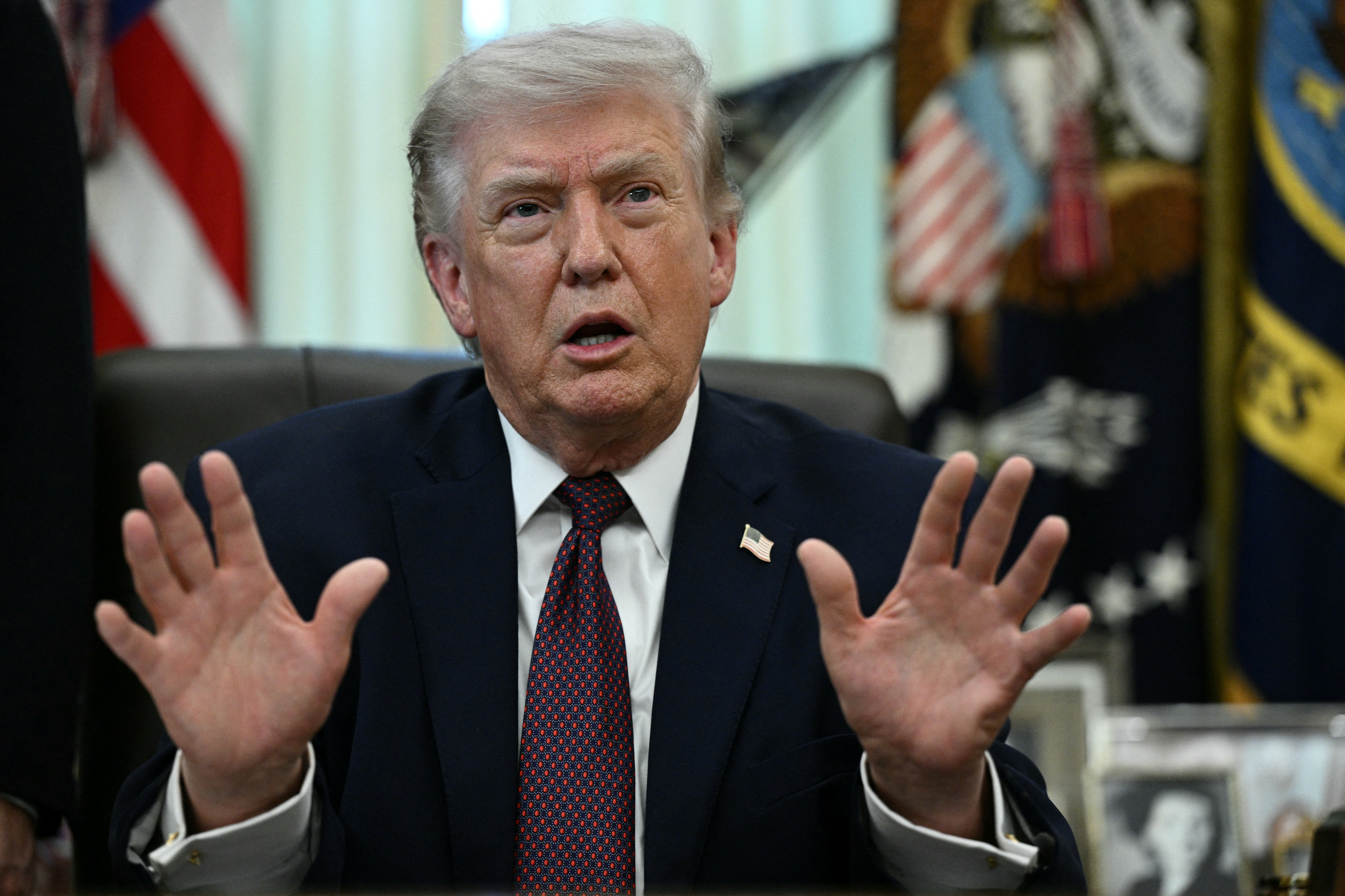 En person i dress snakker med hendene hevet i en formell kontorsetting