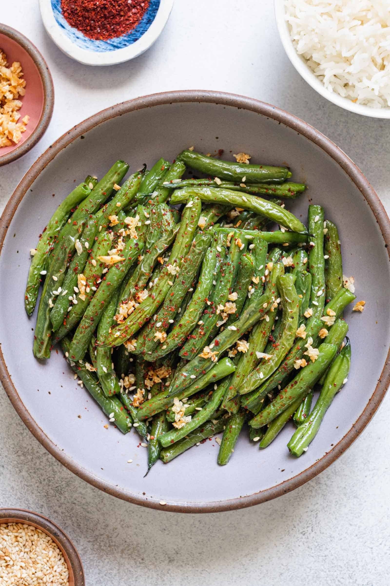 A plate of sautéed green beans garnished with crushed nuts