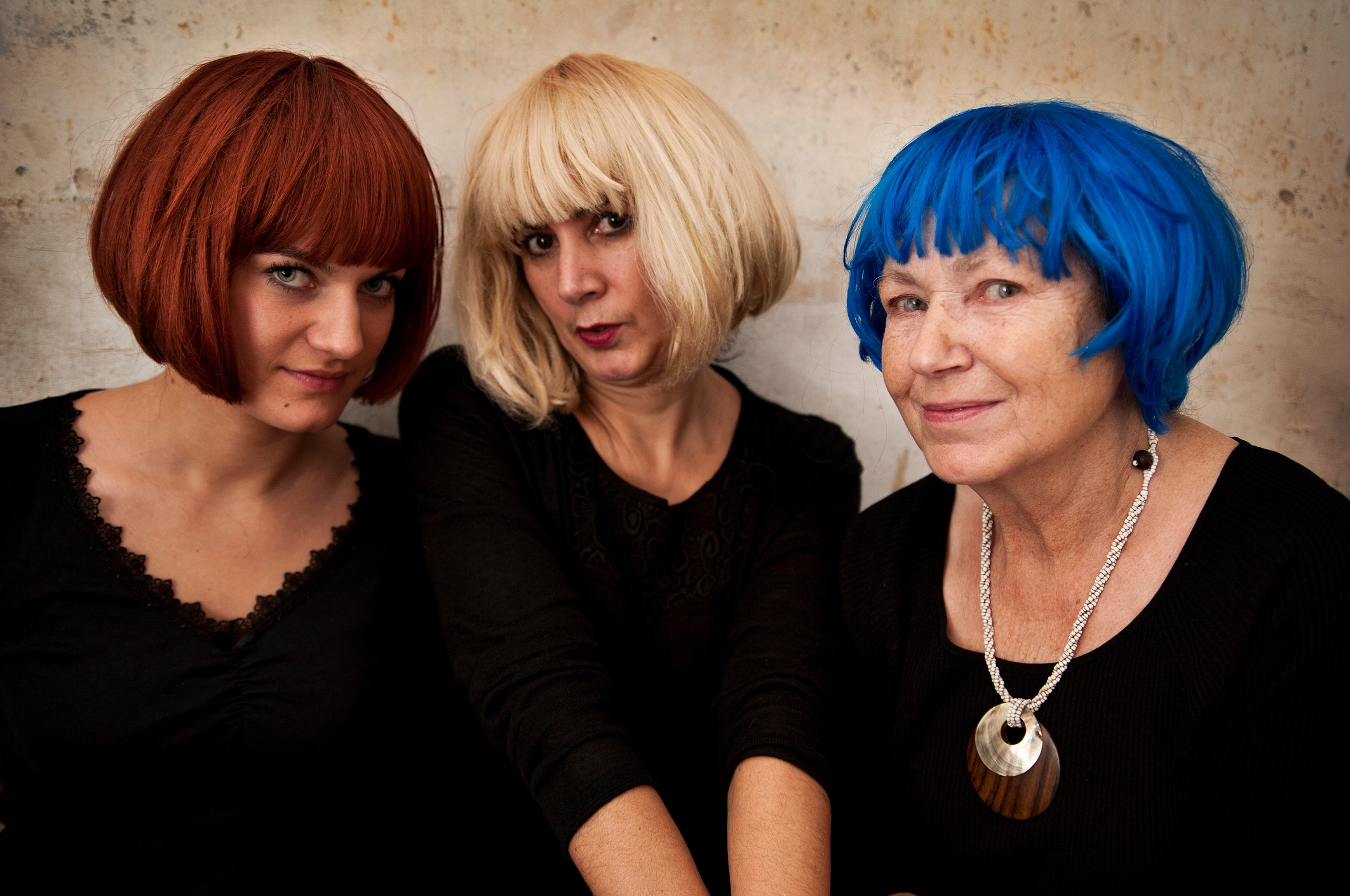 Three radical wearing bob wigs successful red, blonde, and blue, dressed successful achromatic tops, airs unneurotic indoors