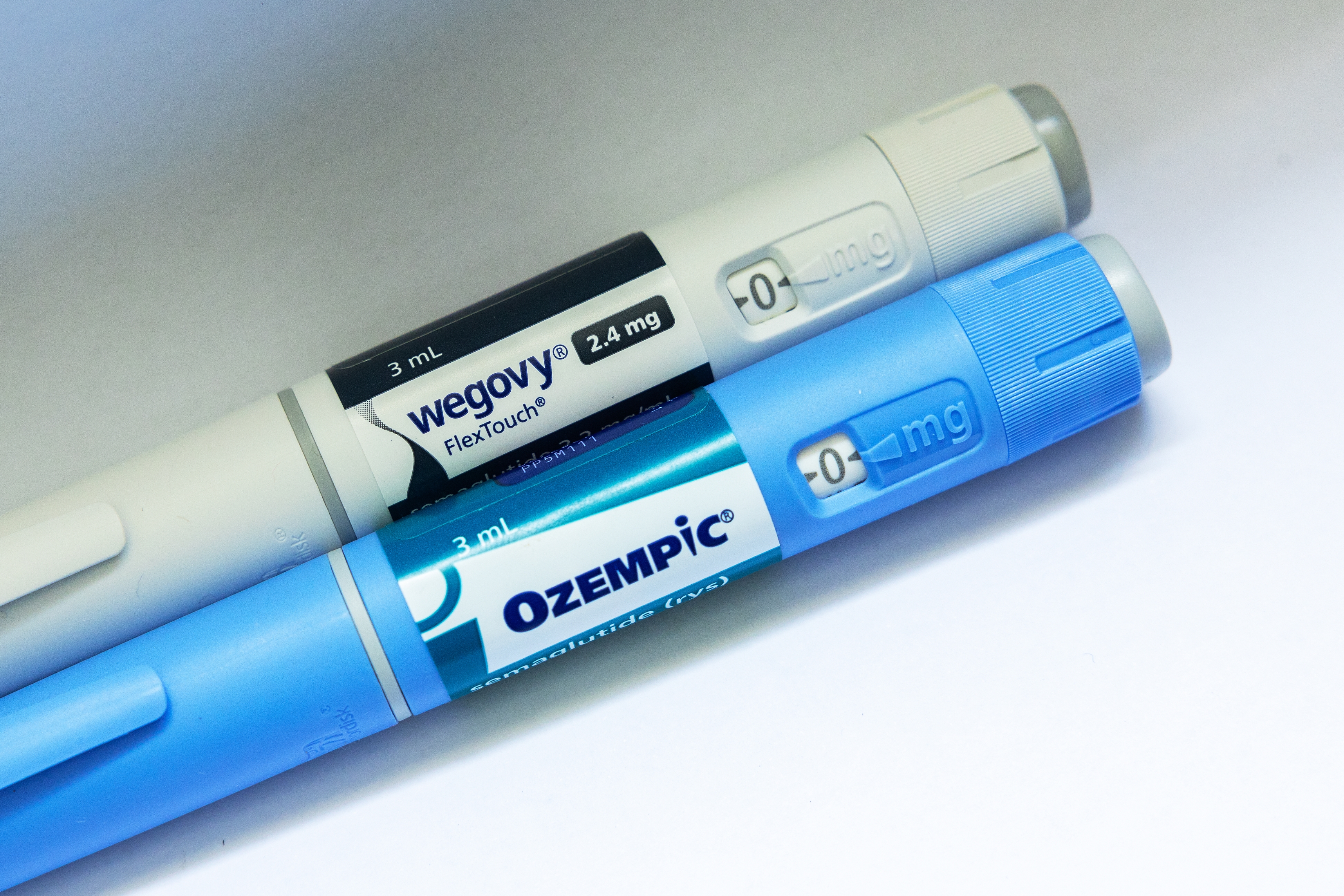Two medicine  pens labeled Wegovy and Ozempic, some  displaying dosage information