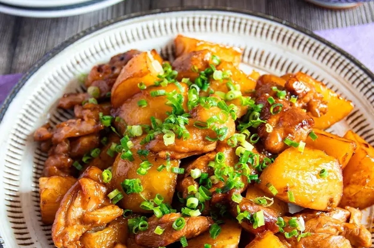 皿に盛られた新じゃがいもと鶏肉の料理、ねぎがトッピングされている。