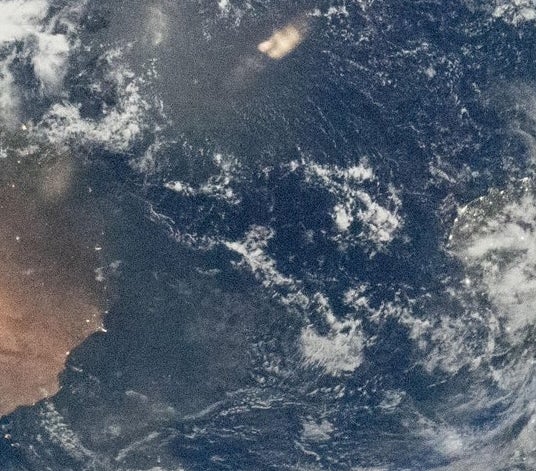 Utsikt over jorden fra verdensrommet, som viser planetens krumning med synlige skyer og landmasser. Bildet fremhever jordens skjønnhet og vidstrakthet