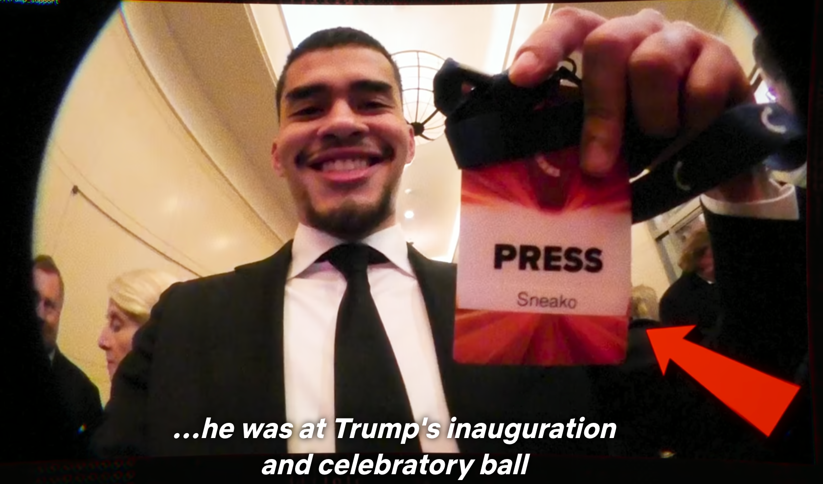 Man wearing a suit holds a property badge labeled "Sneako" astatine an event, smiling, with caption astir Trump's inauguration