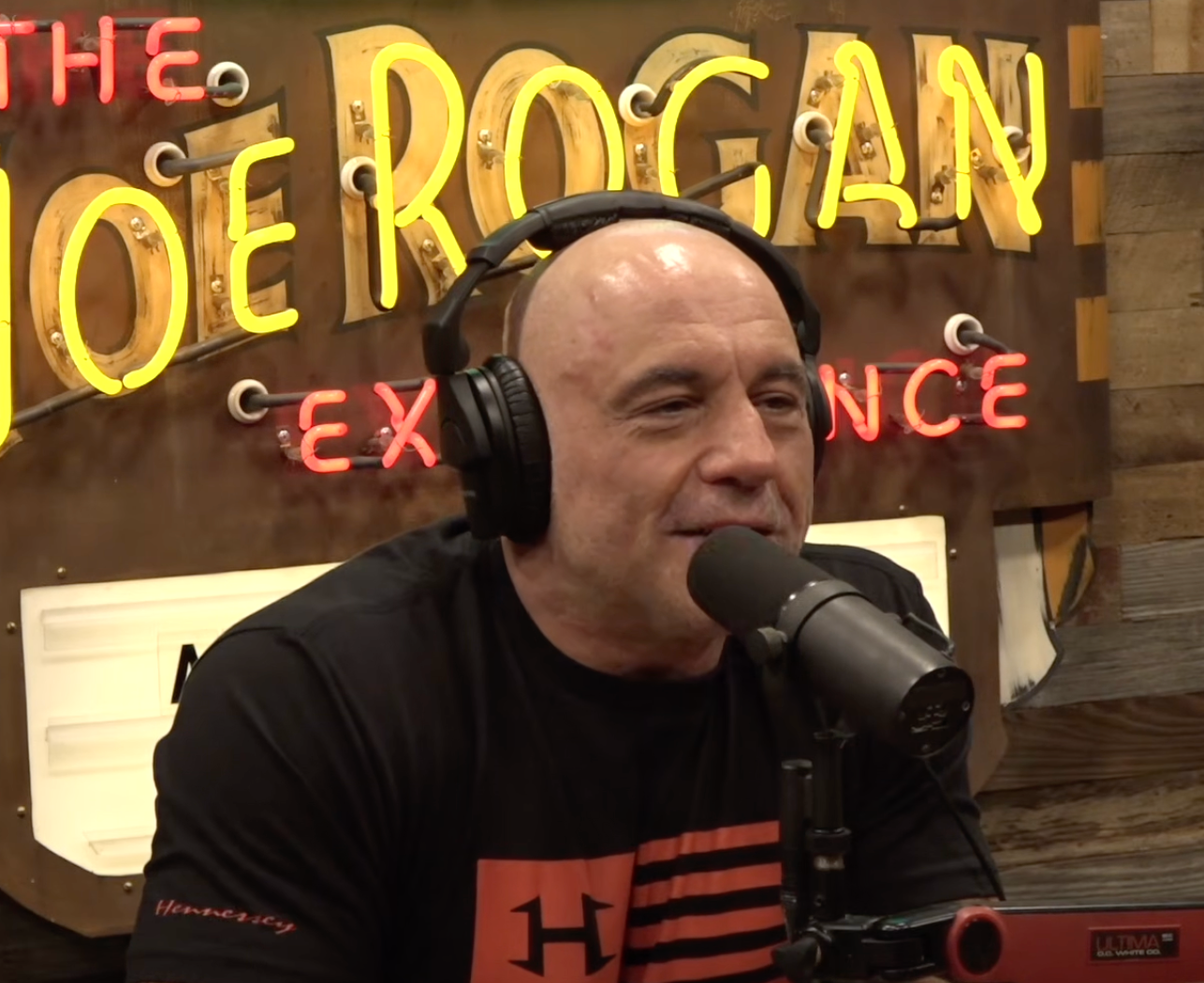 Person speaking into a microphone with headphones on, successful  a workplace  mounting  with a neon motion   successful  the background