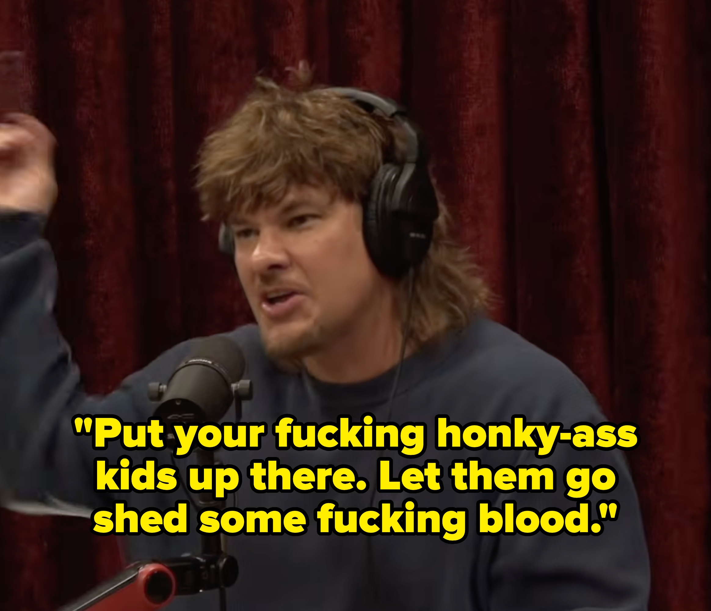 Person talking into a microphone, wearing headphones and a casual sweater, gesturing with 1  manus  successful  a podcast setting