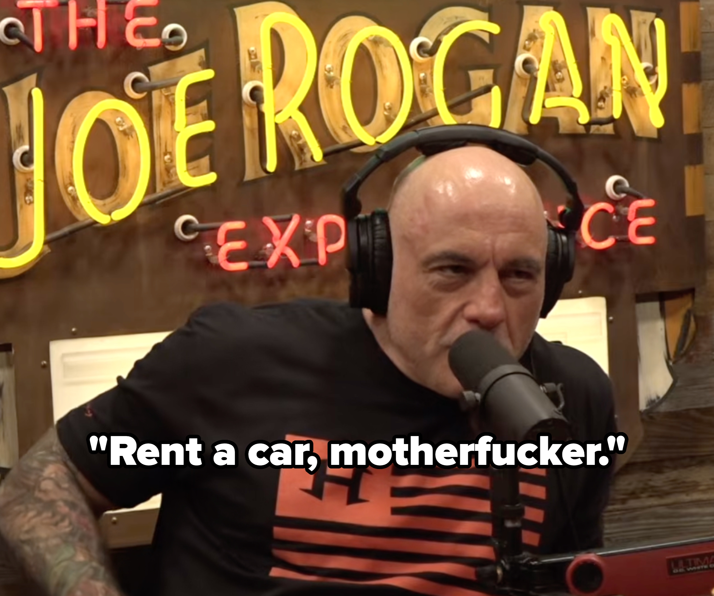 A idiosyncratic   with a microphone wearing headphones, seated successful  beforehand   of a motion   that reads "The Joe Rogan Experience."