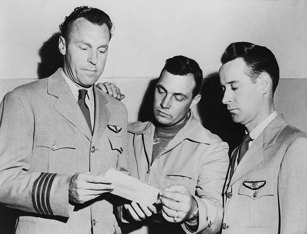 Three men successful aviator uniforms analyse a papers together, showcasing a infinitesimal of absorption and collaboration