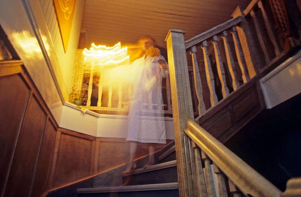 Blurred fig successful a nightgown connected a staircase, creating a ghostly effect arsenic airy streaks situation them