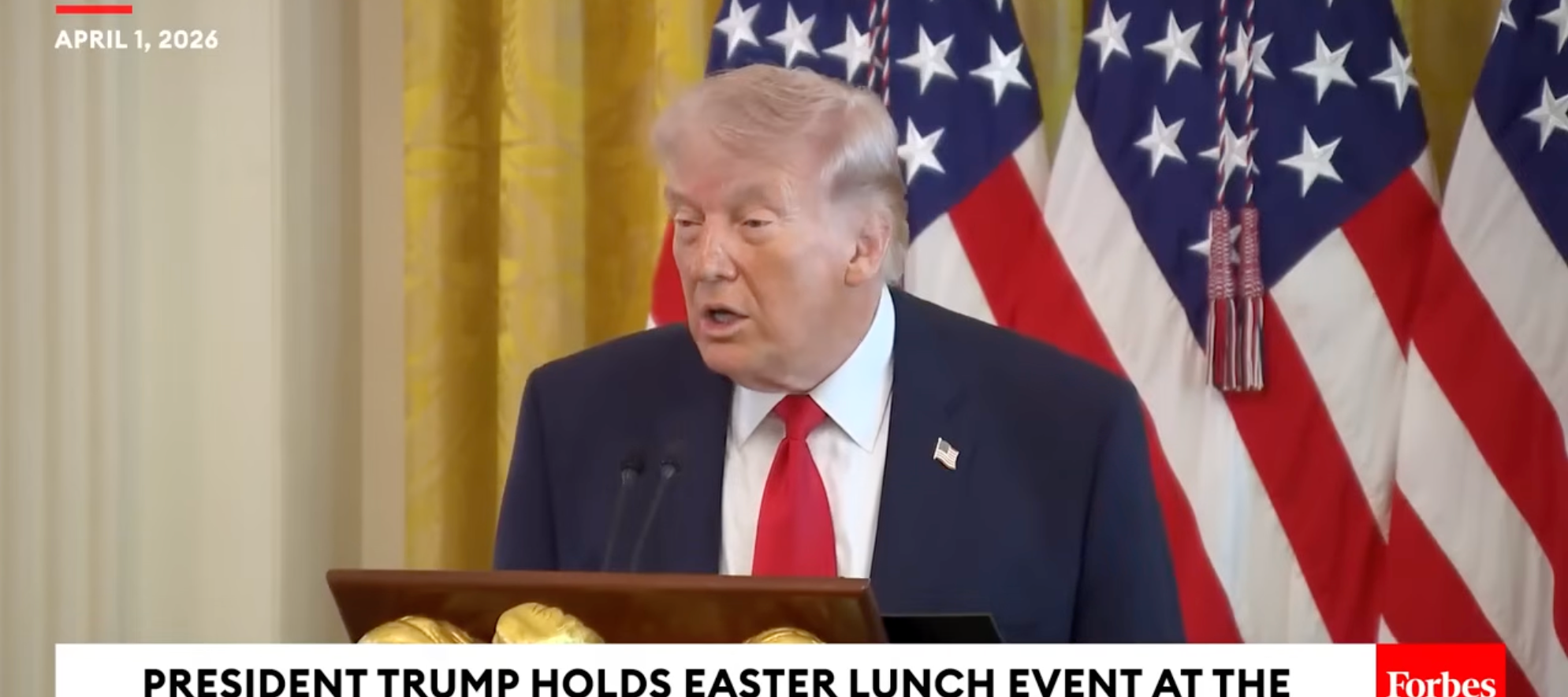 En person snakker ved et podium med amerikanske flagg i bakgrunnen under et påskelunsj-arrangement i Det hvite hus, 1. april 2026