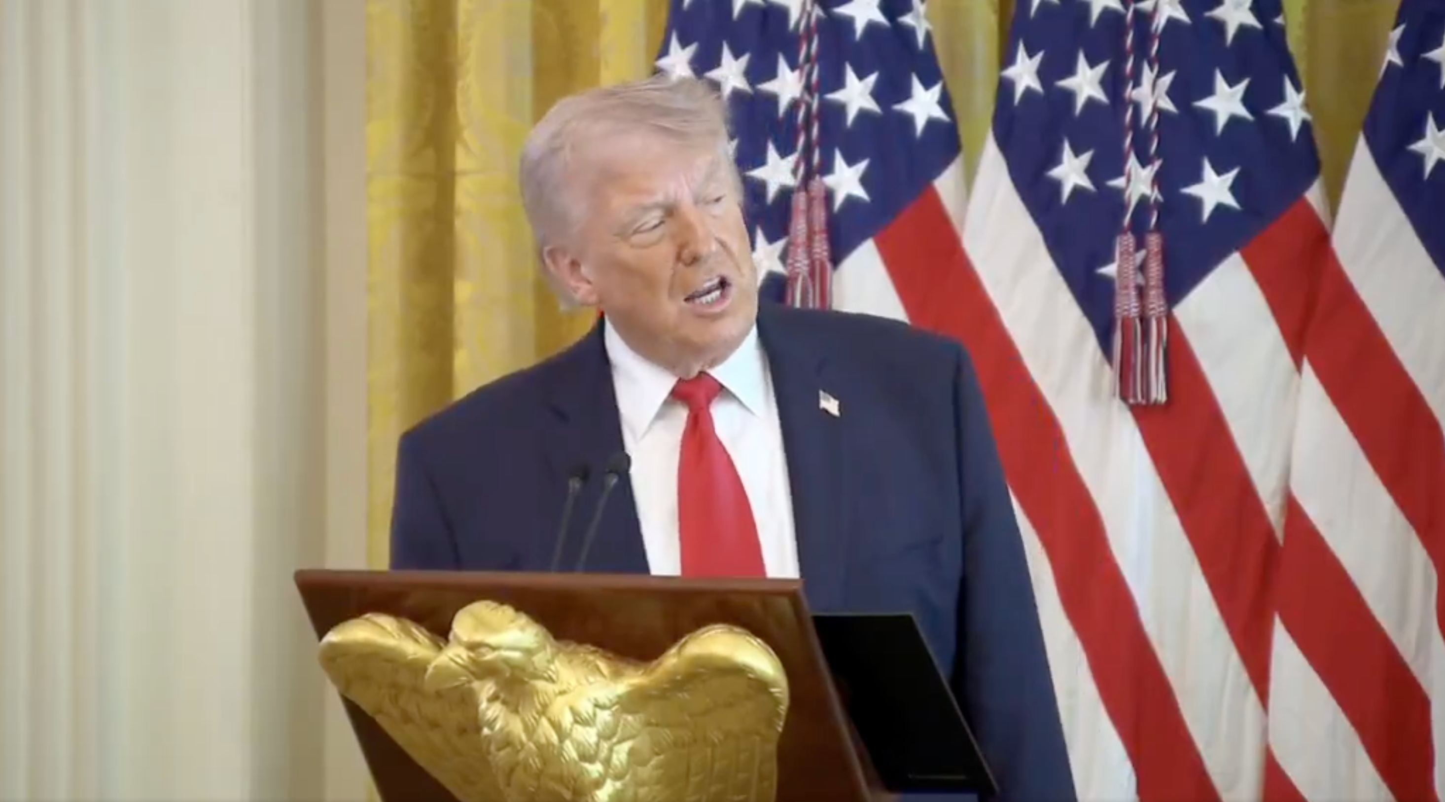 A idiosyncratic speaks astatine a podium with U.S. flags successful the inheritance during a ceremonial event