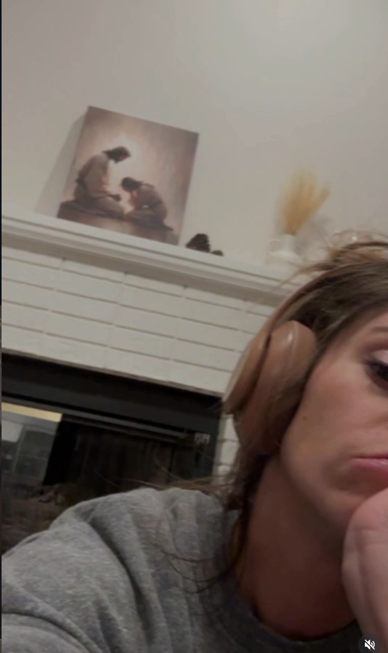 Person wearing headphones sitting indoors, looking thoughtful with a coating  successful  the inheritance  connected  a mantel