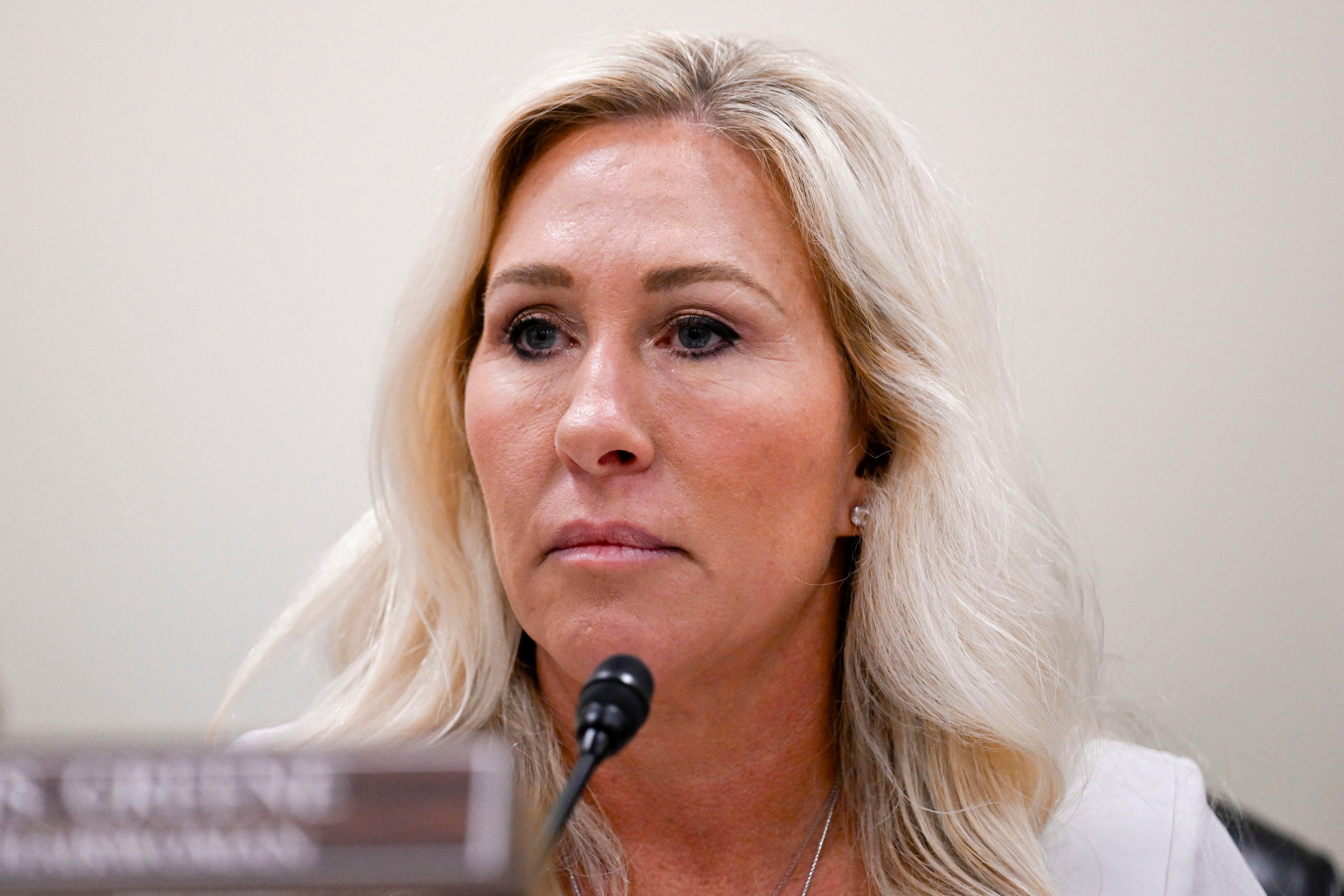 En person snakker ved en mikrofon under en formell begivenhet eller et møte, og virker fokusert