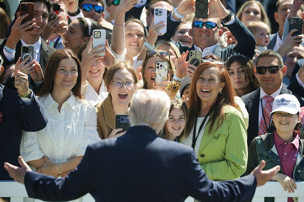 En offentlig person hilser på en entusiastisk mengde mennesker som tar bilder med smarttelefoner