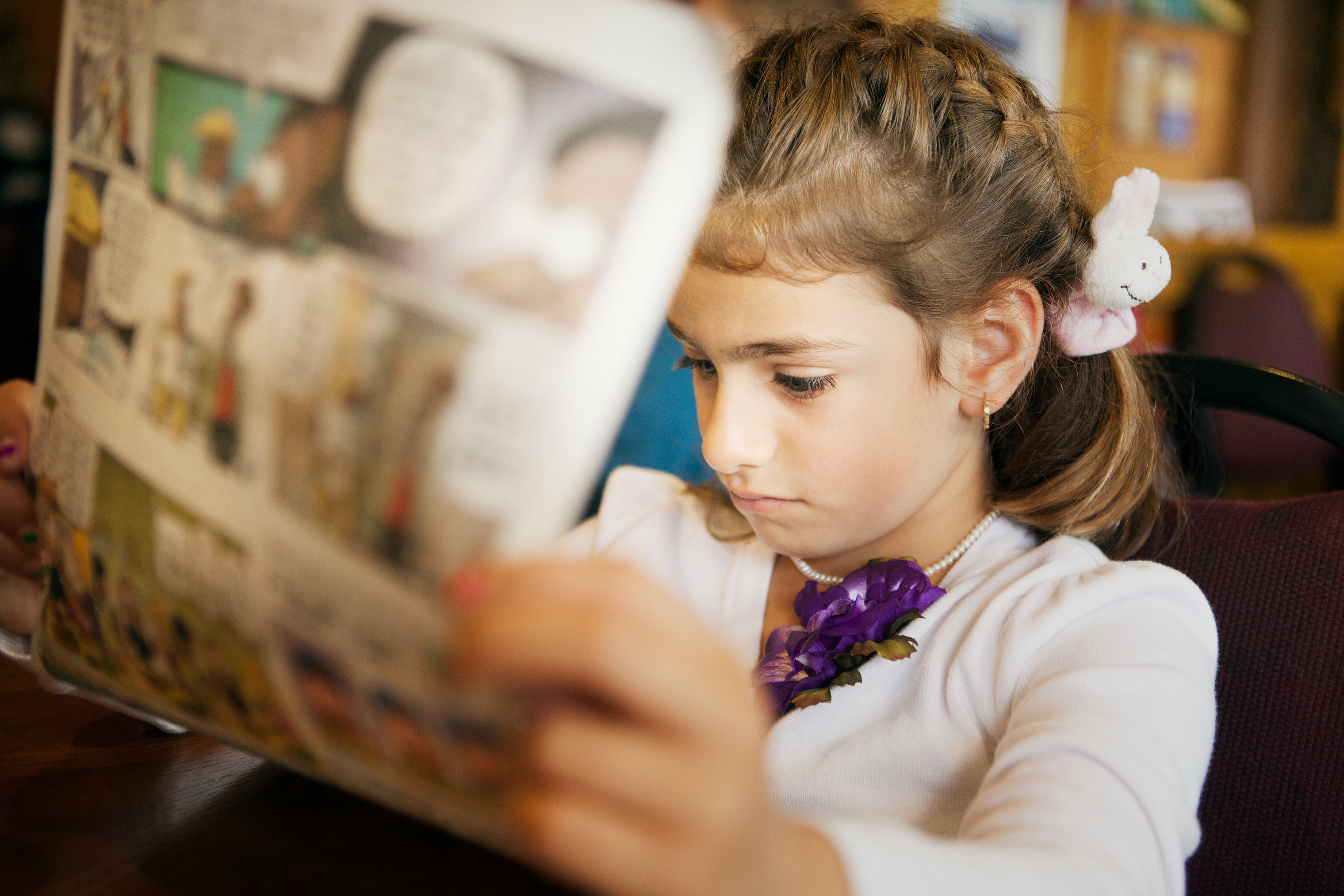 Young miss engrossed successful speechmaking a comic publication with braided hairsbreadth and a tiny artifact clipped on