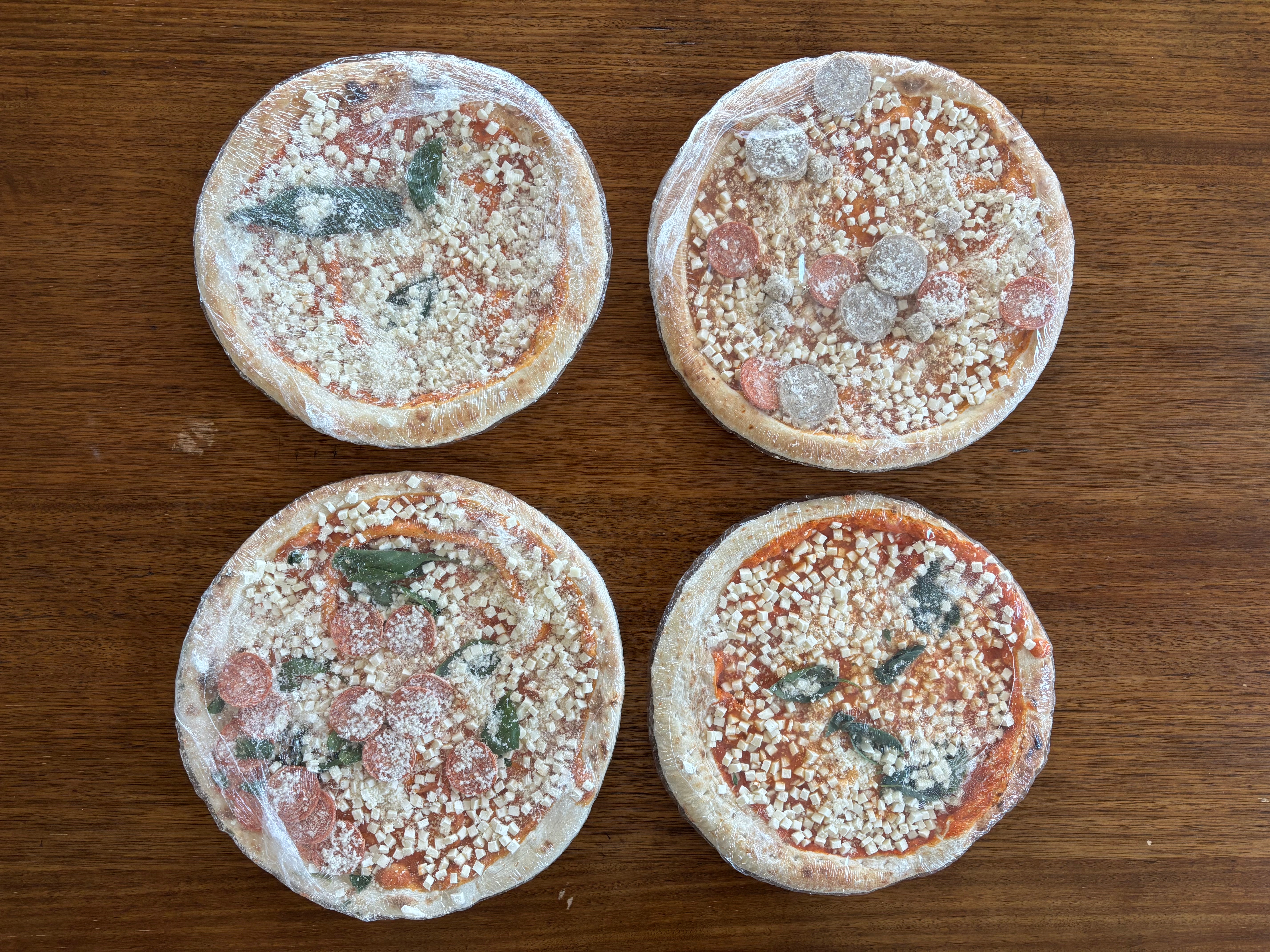 Four frozen mini pizzas with various toppings on a wooden surface
