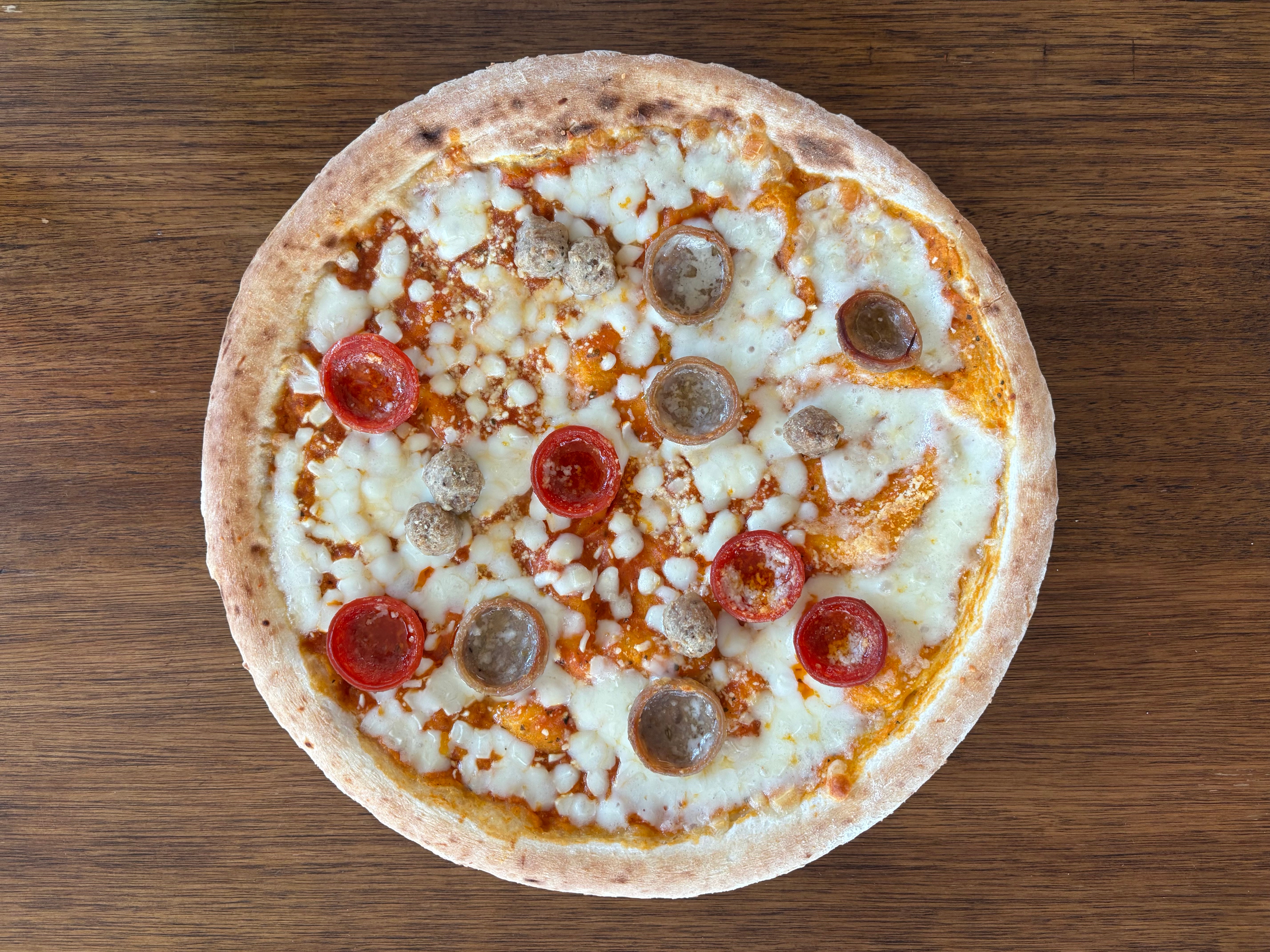 Pizza with cheese, pepperoni, and sausage on a wooden table