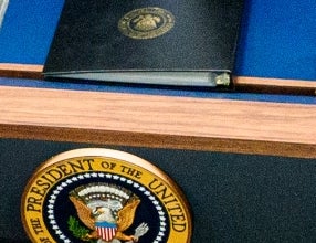 Donald Trump taler på et podium i pressekonferanserommet i Det hvite hus; publikum inkluderer fotografer og enkeltpersoner i formell antrekk