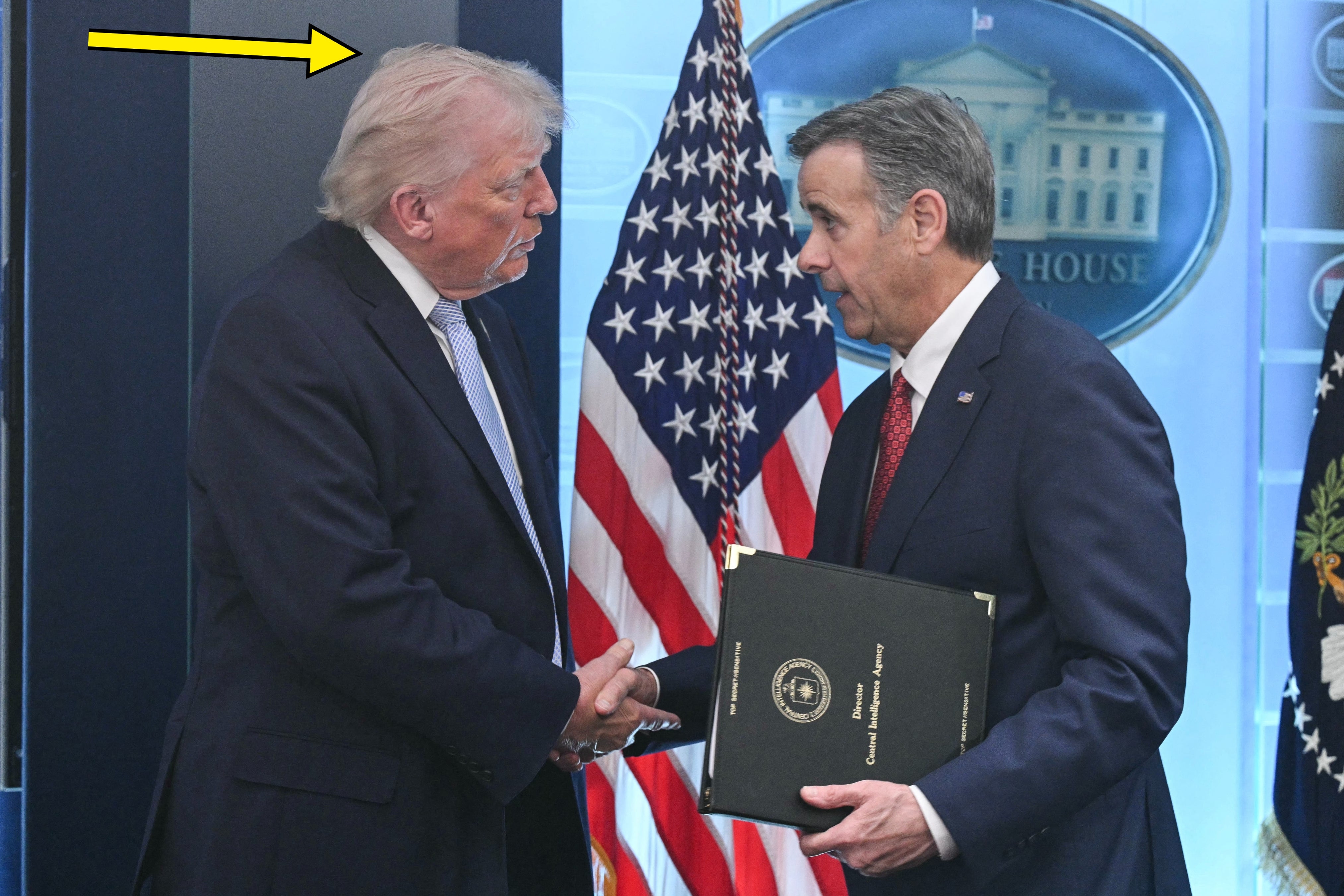 Donald Trump håndhilser på en mann som forlater podiet, en pil peker på det rotete håret hans