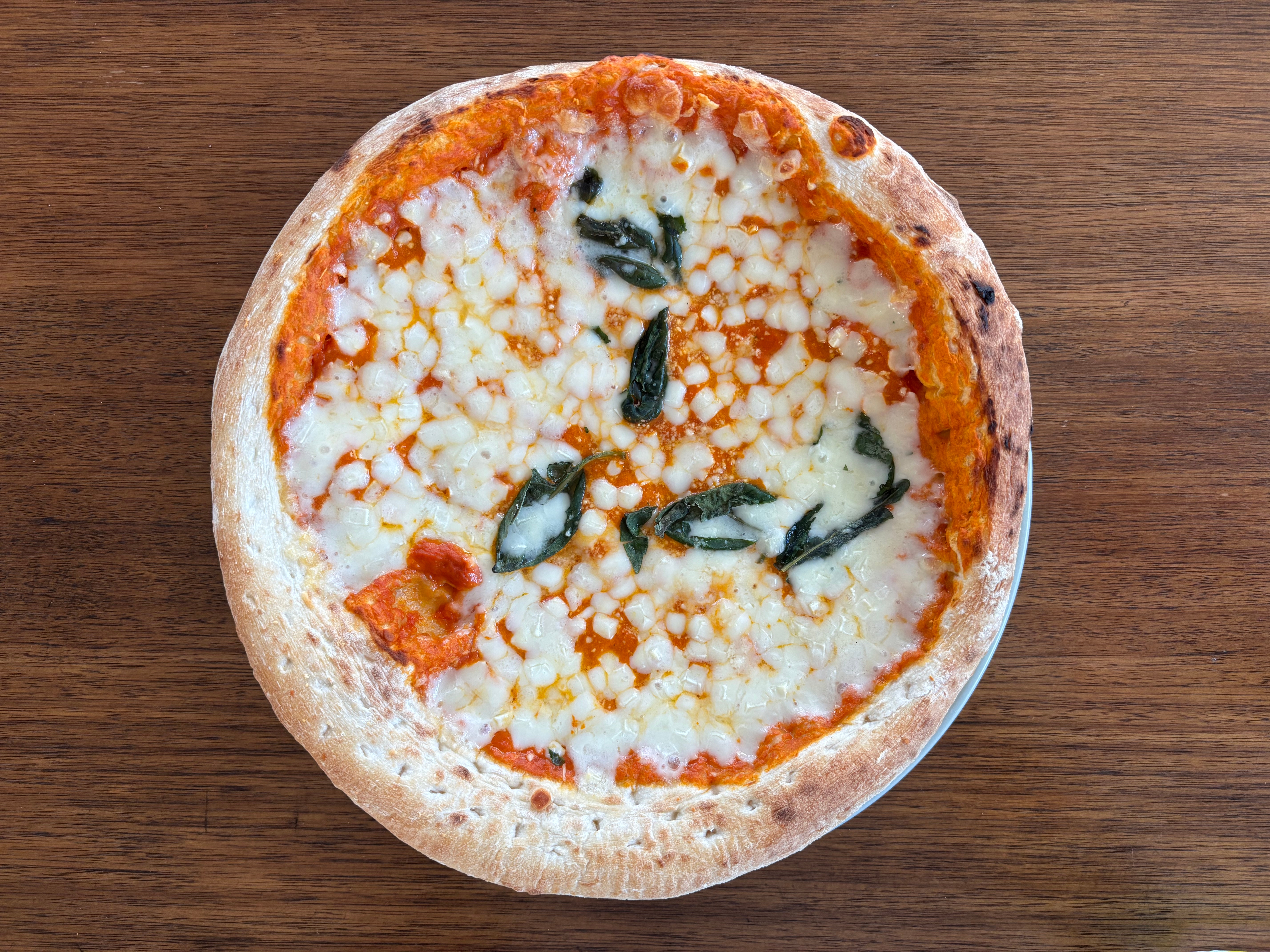 Pizza with melted cheese, tomato sauce, and basil on a wooden table