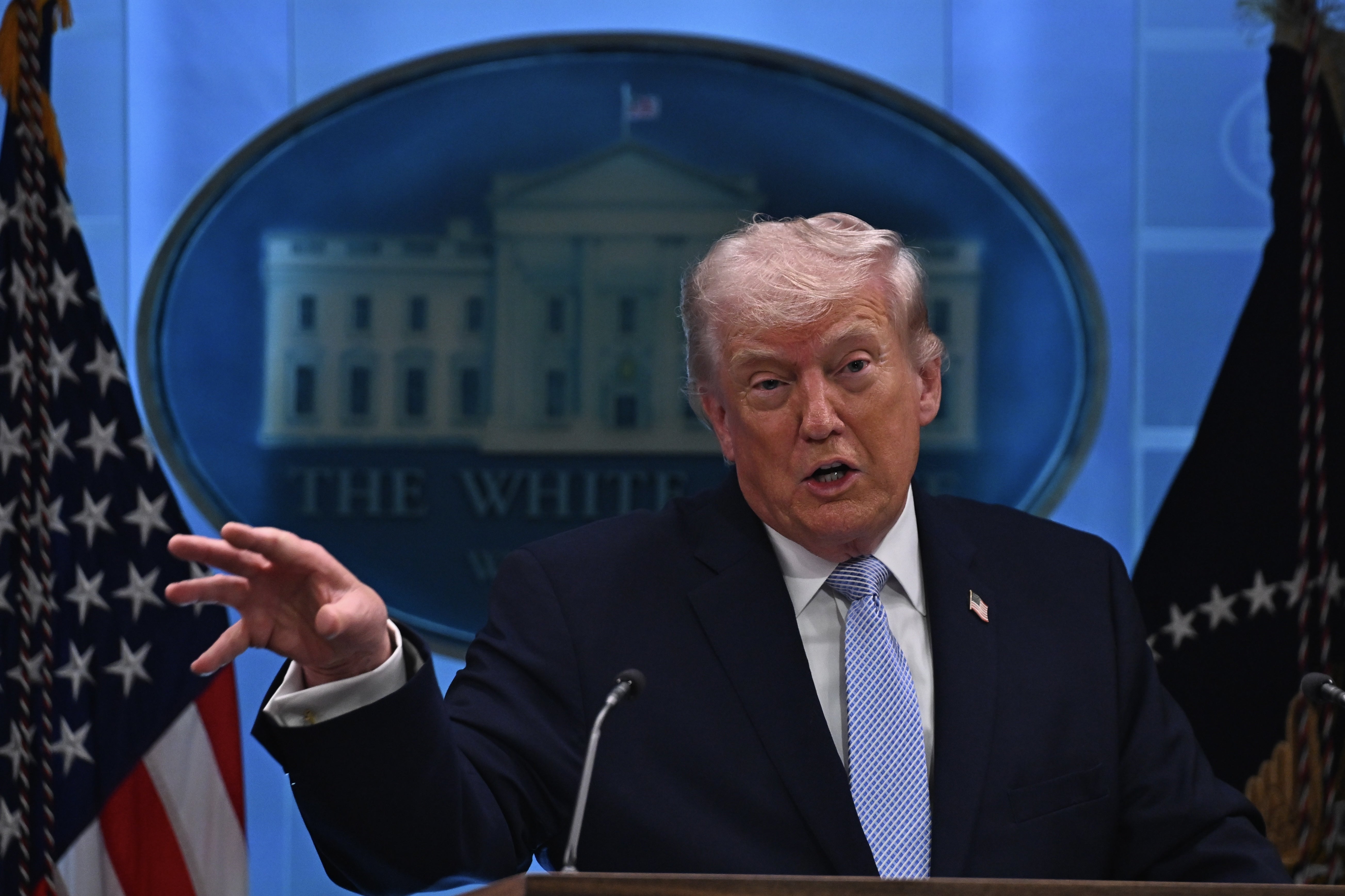 Donald Trump i dress taler ved et podium i et presserom med et emblem fra Det hvite hus i bakgrunnen