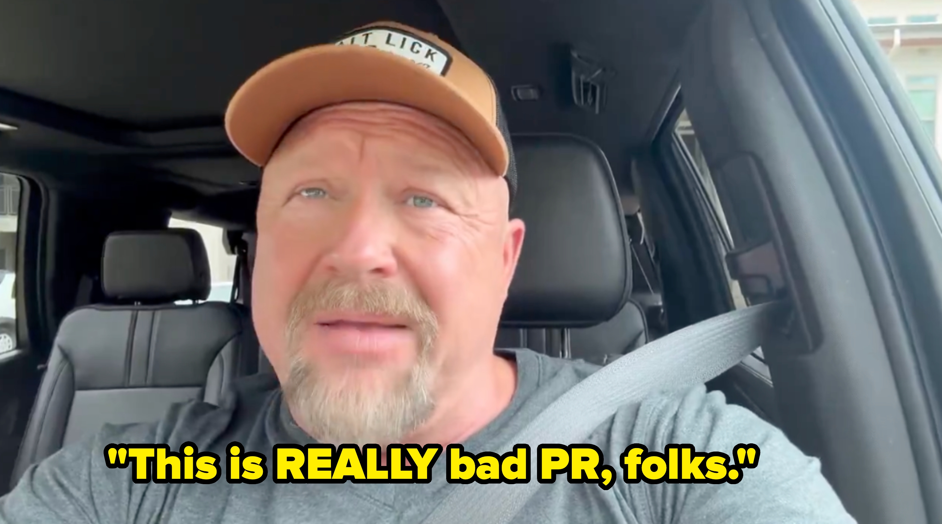 Man wearing a headdress  sits successful  a car, looking towards the camera