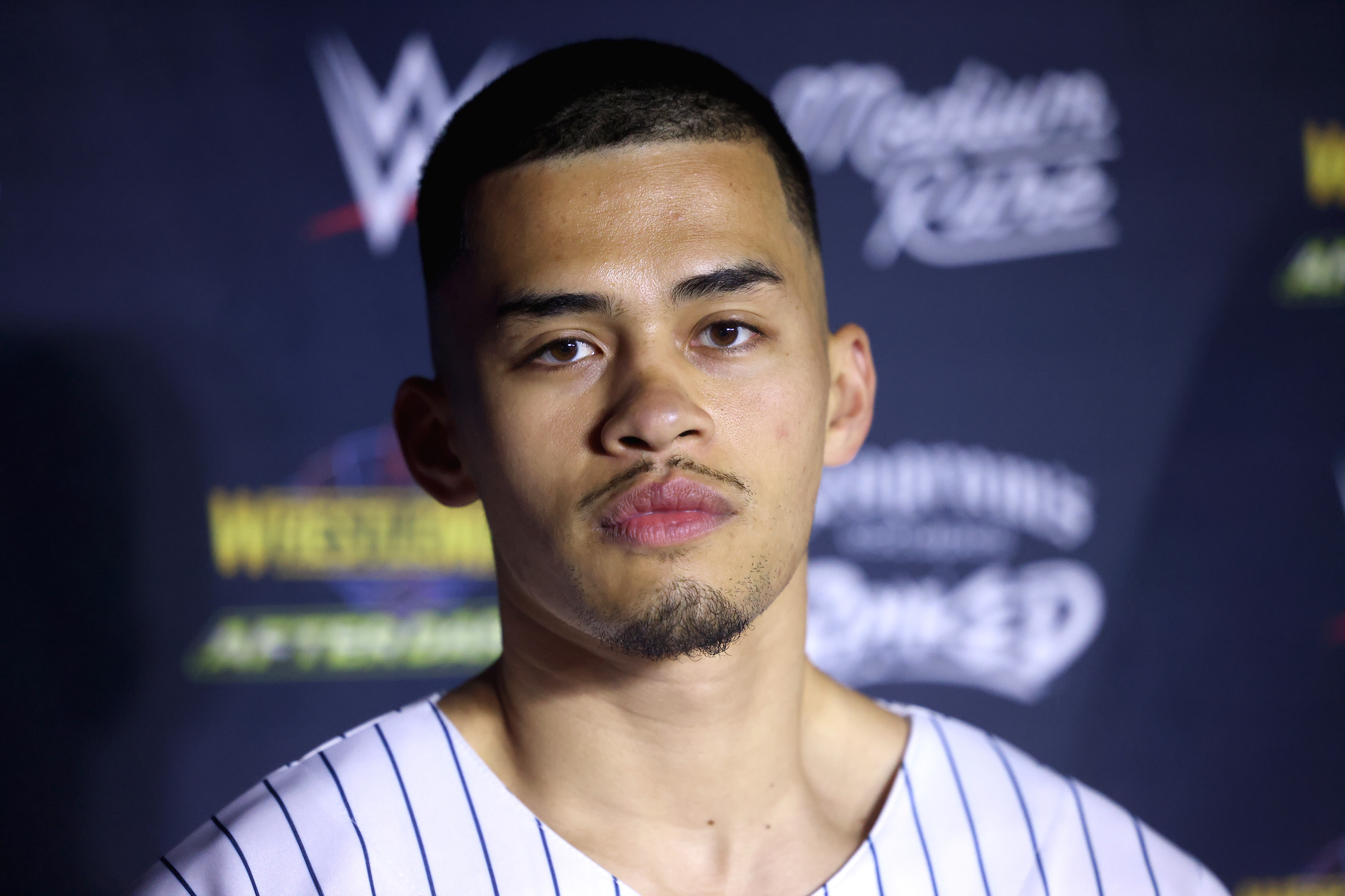 Person astatine a WWE lawsuit wearing a pinstripe shirt, posing against a branded backdrop