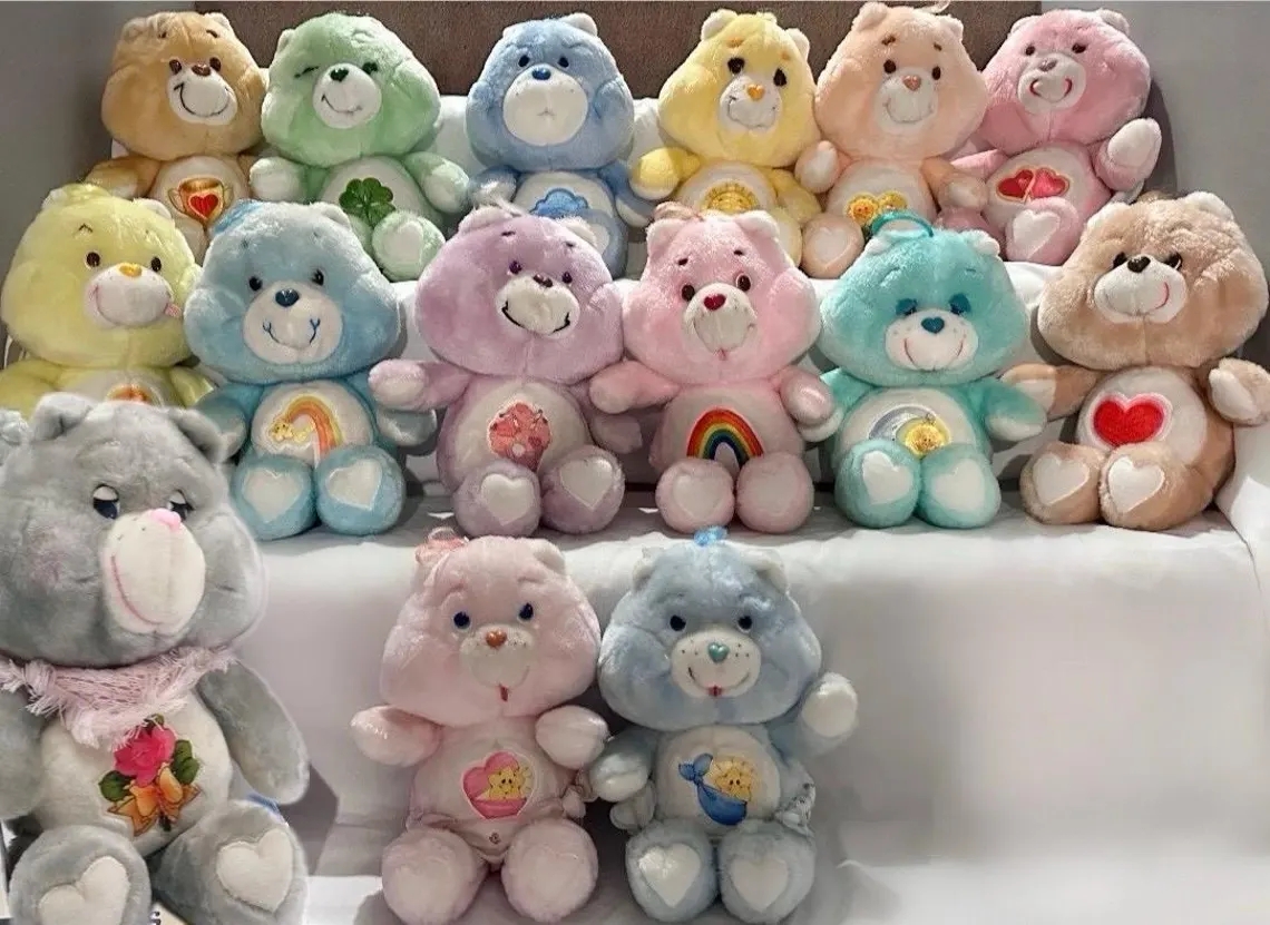 Collection of vintage Care Bears plush toys, each with unsocial symbols connected their bellies, arranged successful rows