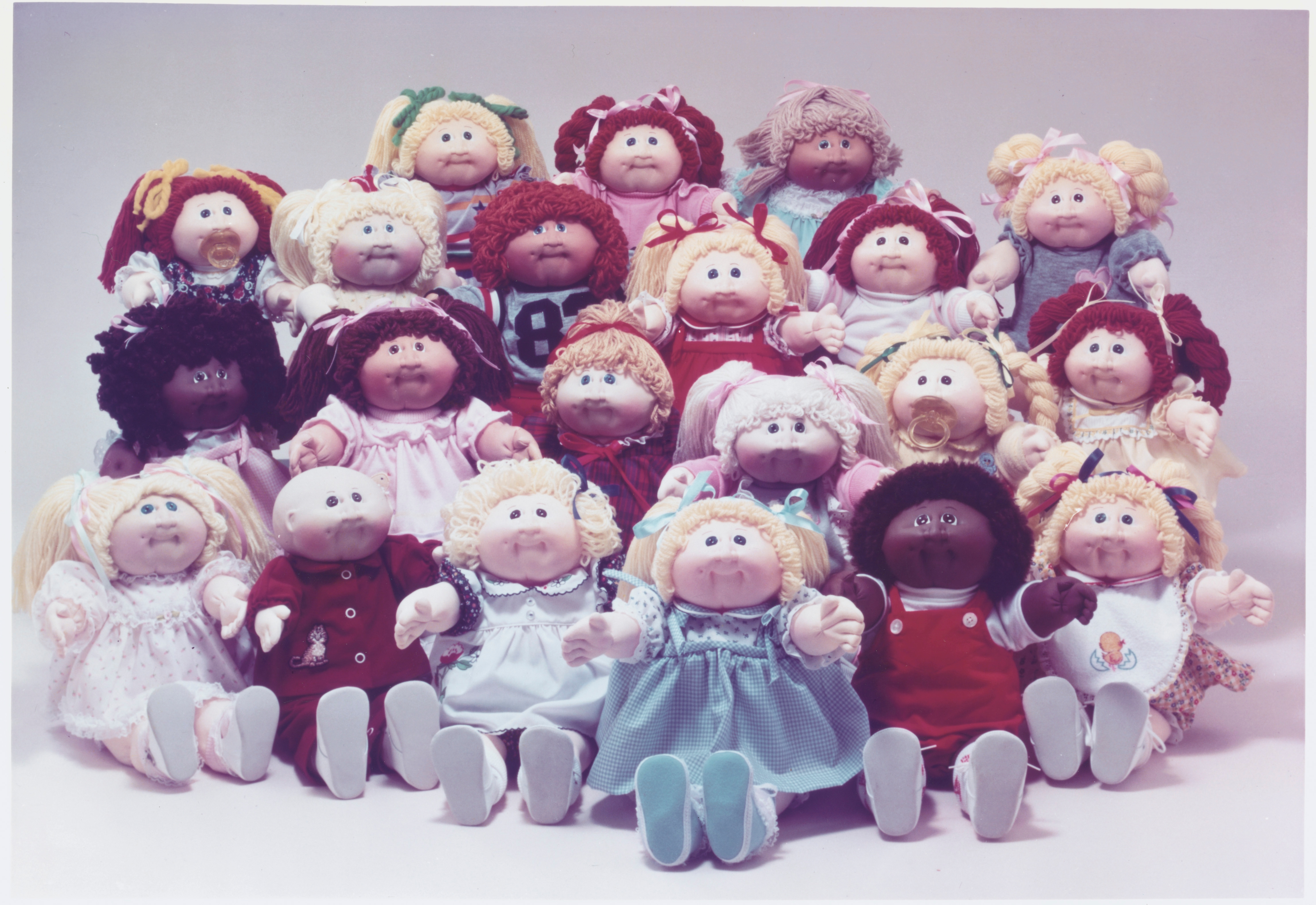 A radical of assorted Cabbage Patch Kids dolls, each with unsocial outfits and hairstyles, sitting unneurotic successful rows for a nostalgic photo