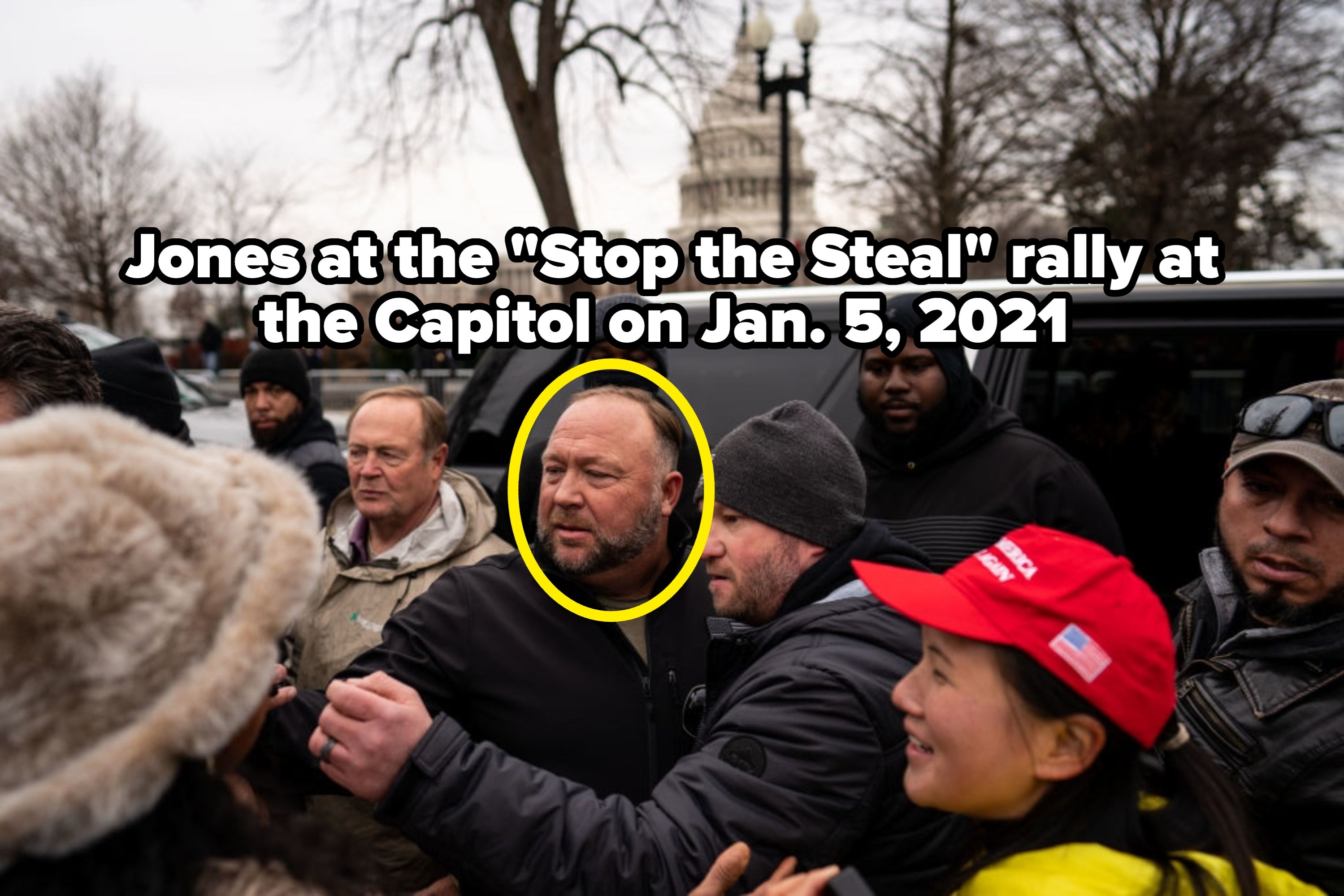 En gruppe mennesker samles utenfor, noen iført vinterklær og hatter, med en stor bygning synlig i bakgrunnen