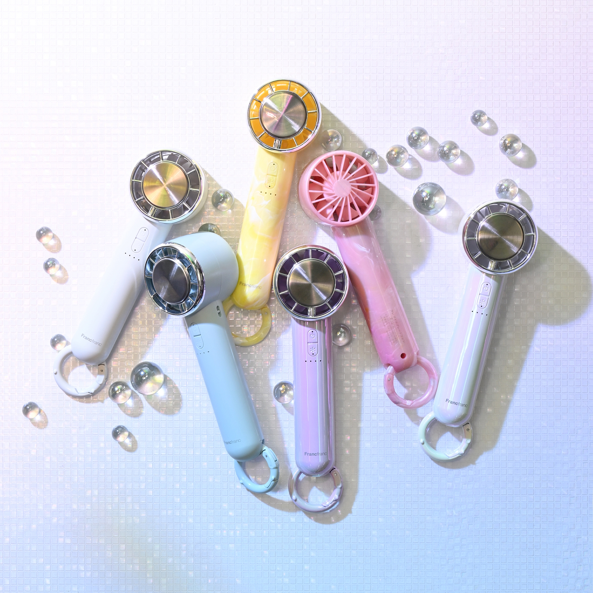 テーブルに並べられた5本のポータブルファンと透明のオブジェクト。