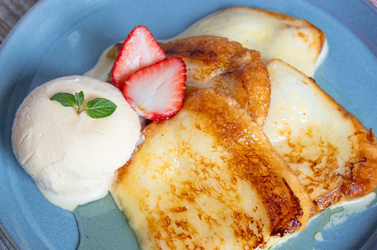 お皿に乗ったバニラアイスクリームとイチゴが添えられたフレンチトースト。