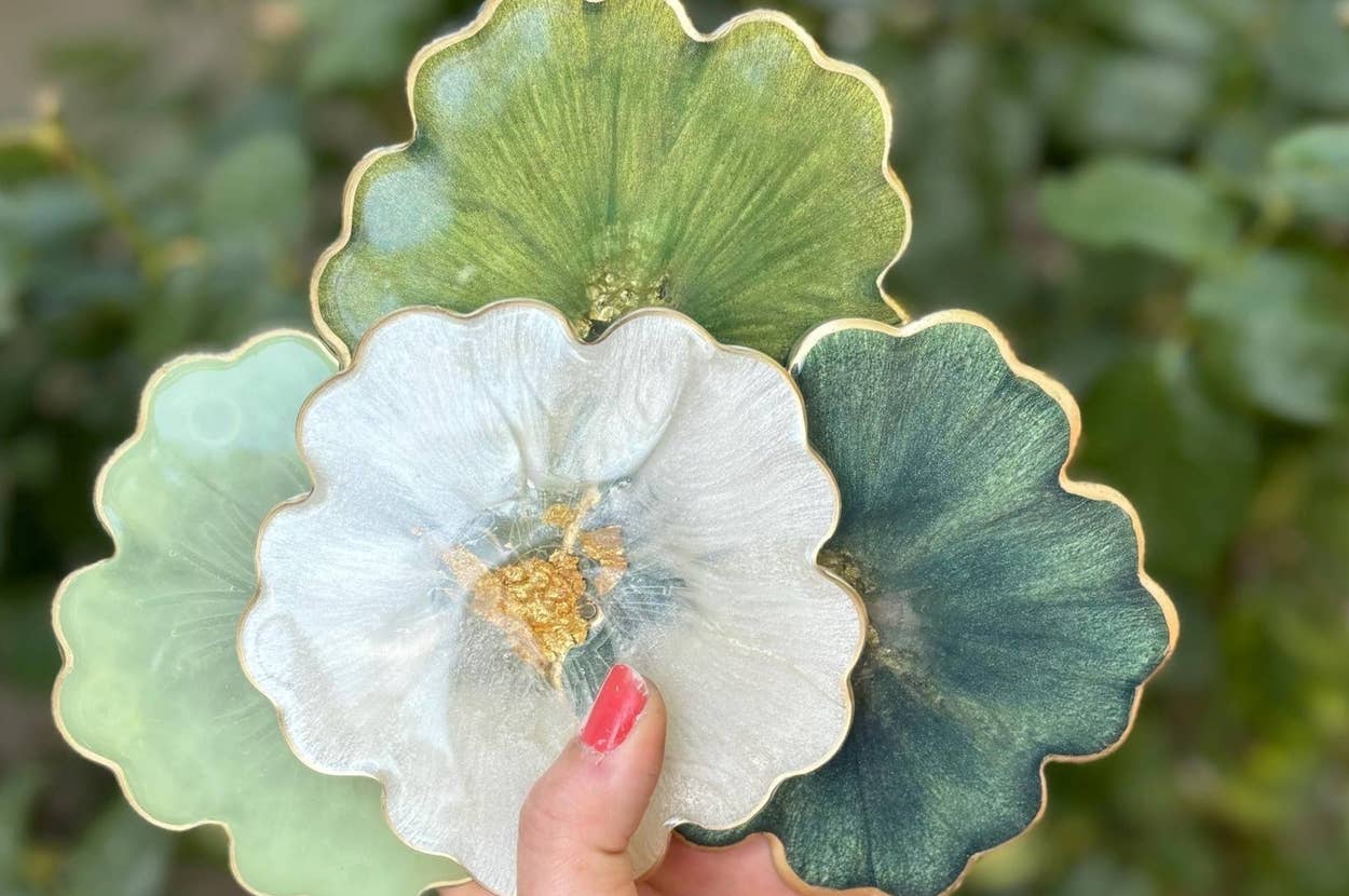 Hand holding artistic coasters resembling flowers; next to floral-patterned Band-Aid box with coordinating bandages