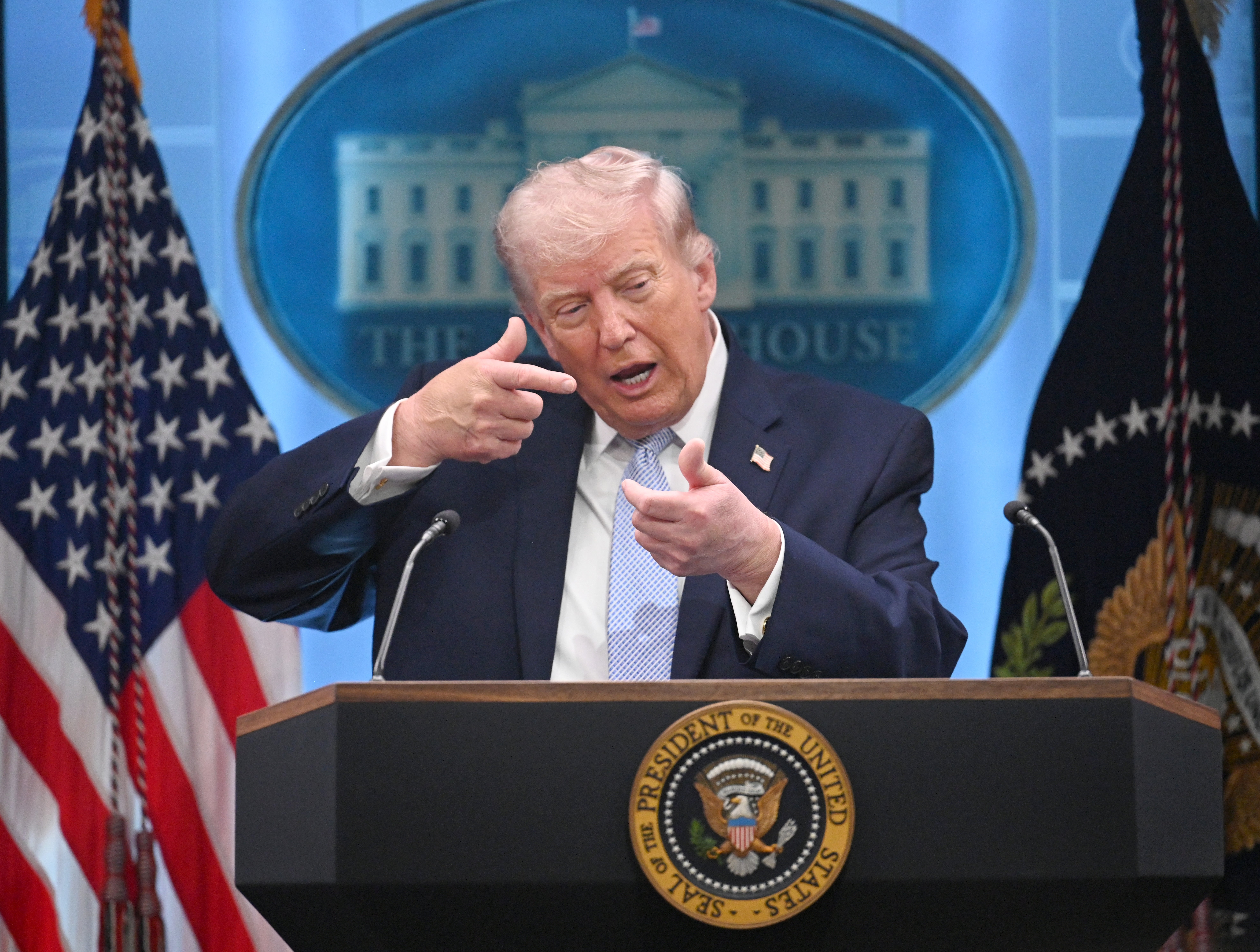 En person på en pressebriefing gjør en gest med hånden, og står på et podium med Det hvite hus-emblemet i bakgrunnen