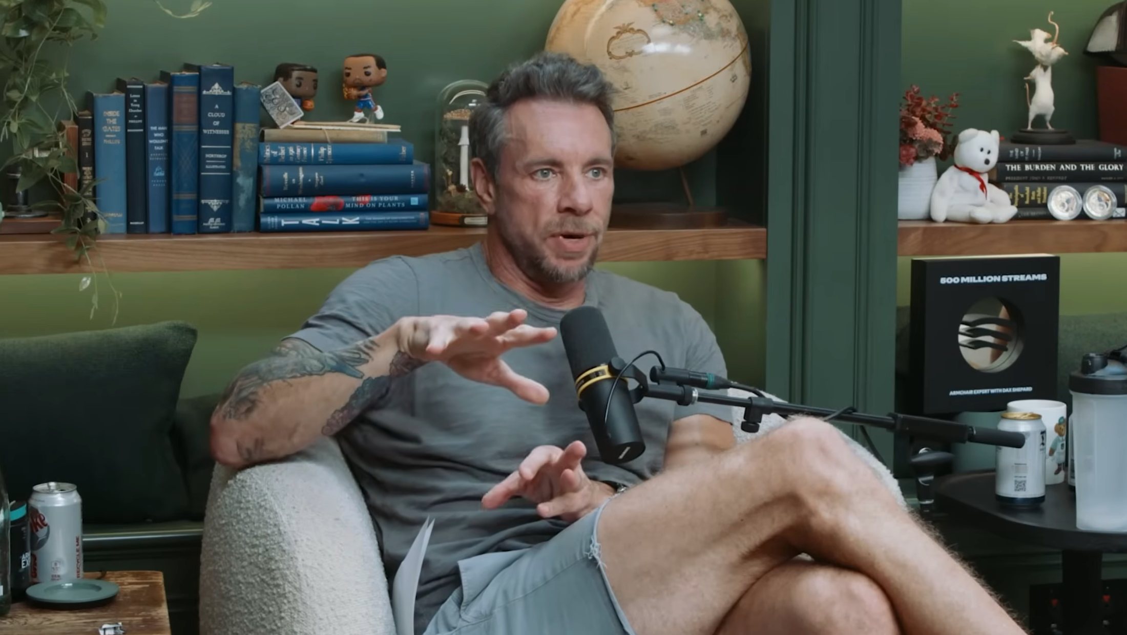 Person seated successful a casual mounting with books and decor successful the background, speaking into a microphone portion gesturing with their hand