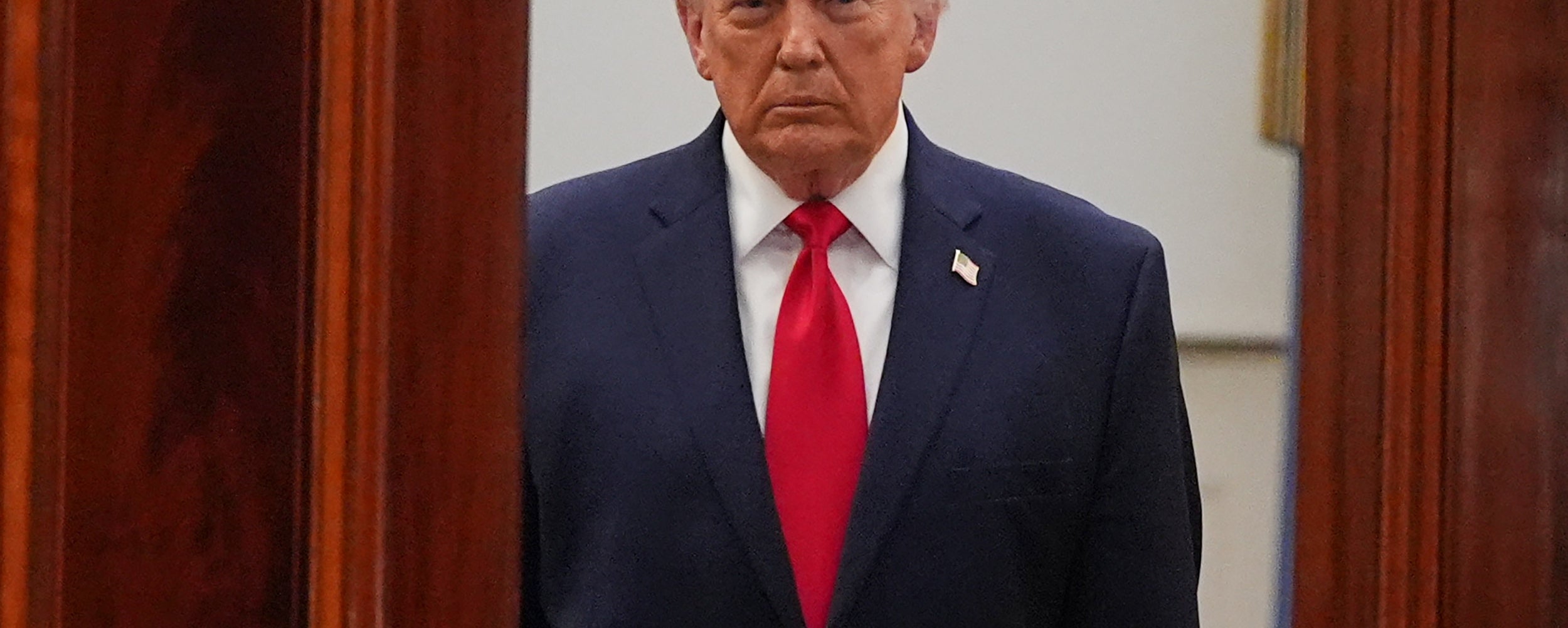 En person i dress og slips står i en døråpning og virker seriøs som en del av en nyhetshendelse