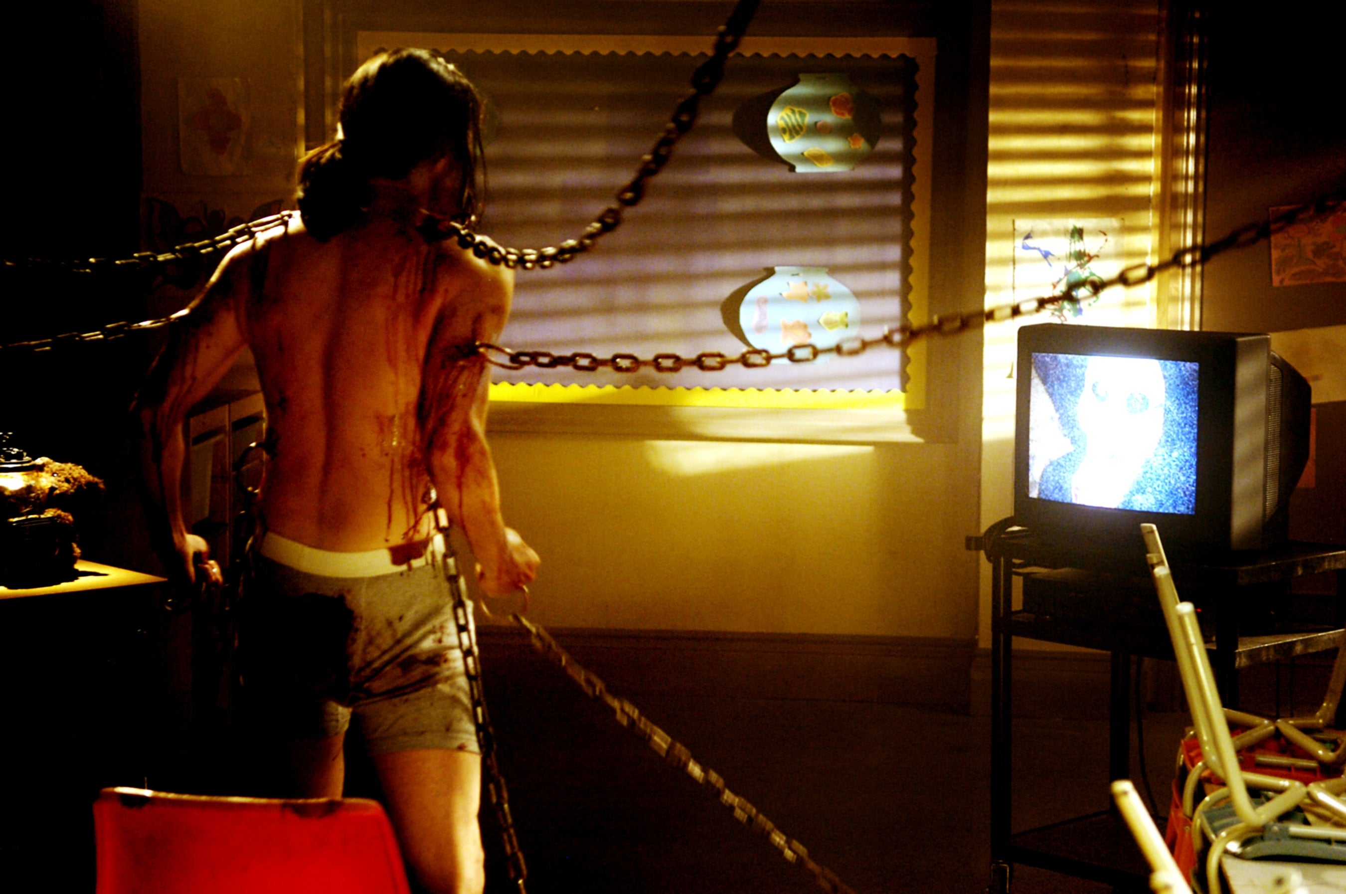 Person successful a acheronian country connected to chains, facing a static-filled TV. Sparse lighting from a window