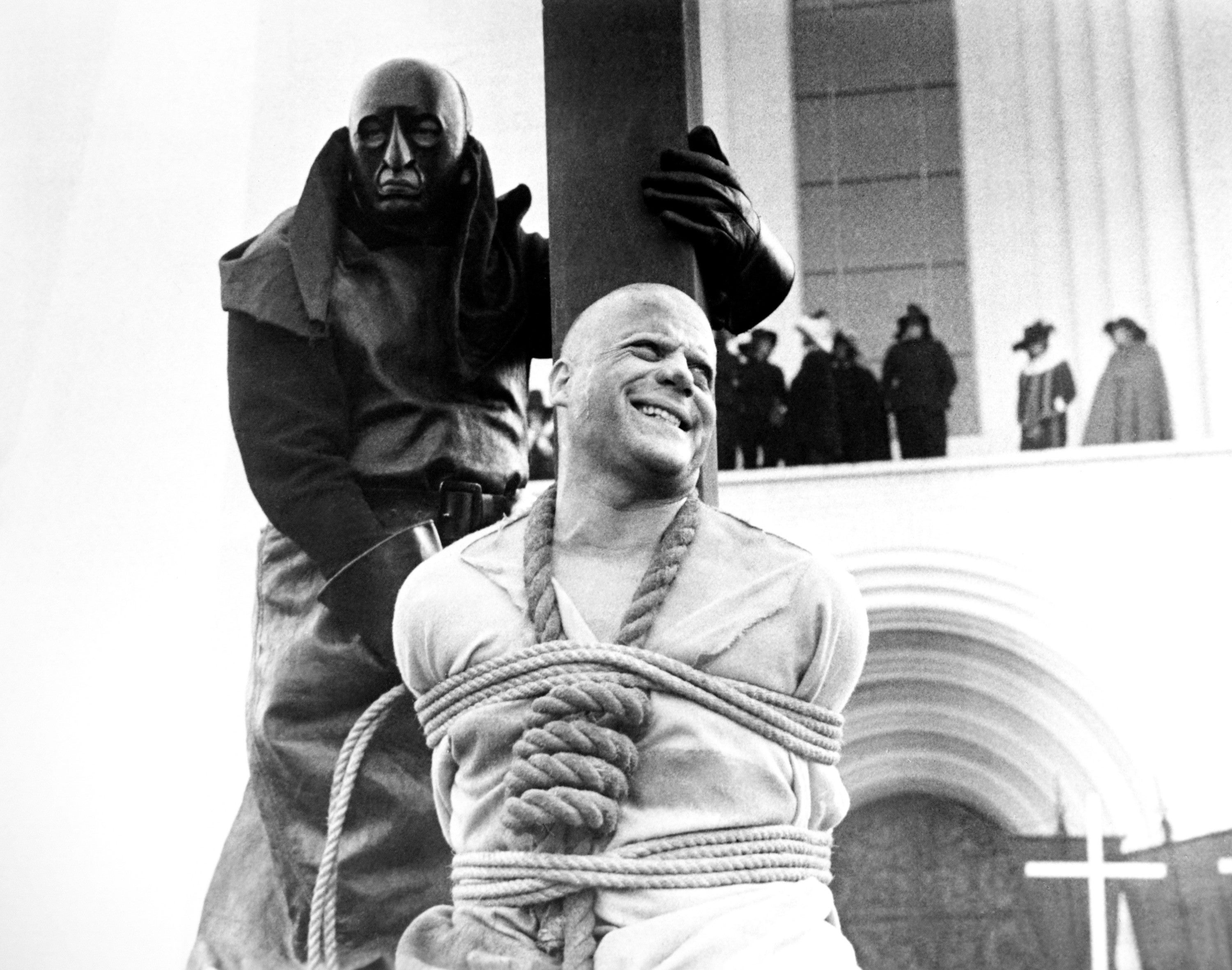 A idiosyncratic tied to a stake, with an executioner nearby, successful a melodramatic country from an aged movie oregon humanities reenactment