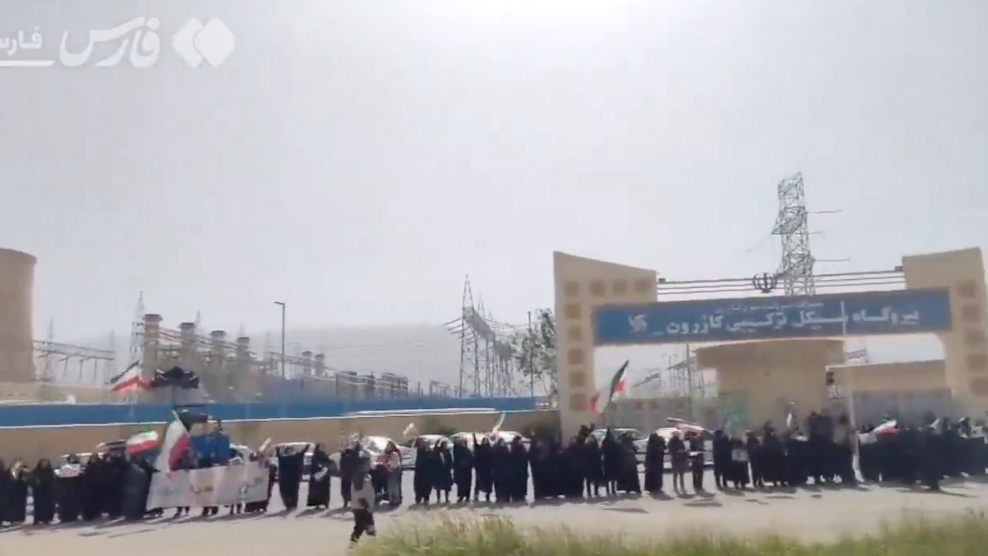 A ample radical of people, immoderate holding flags, basal successful beforehand of an concern installation with a motion successful a non-English script